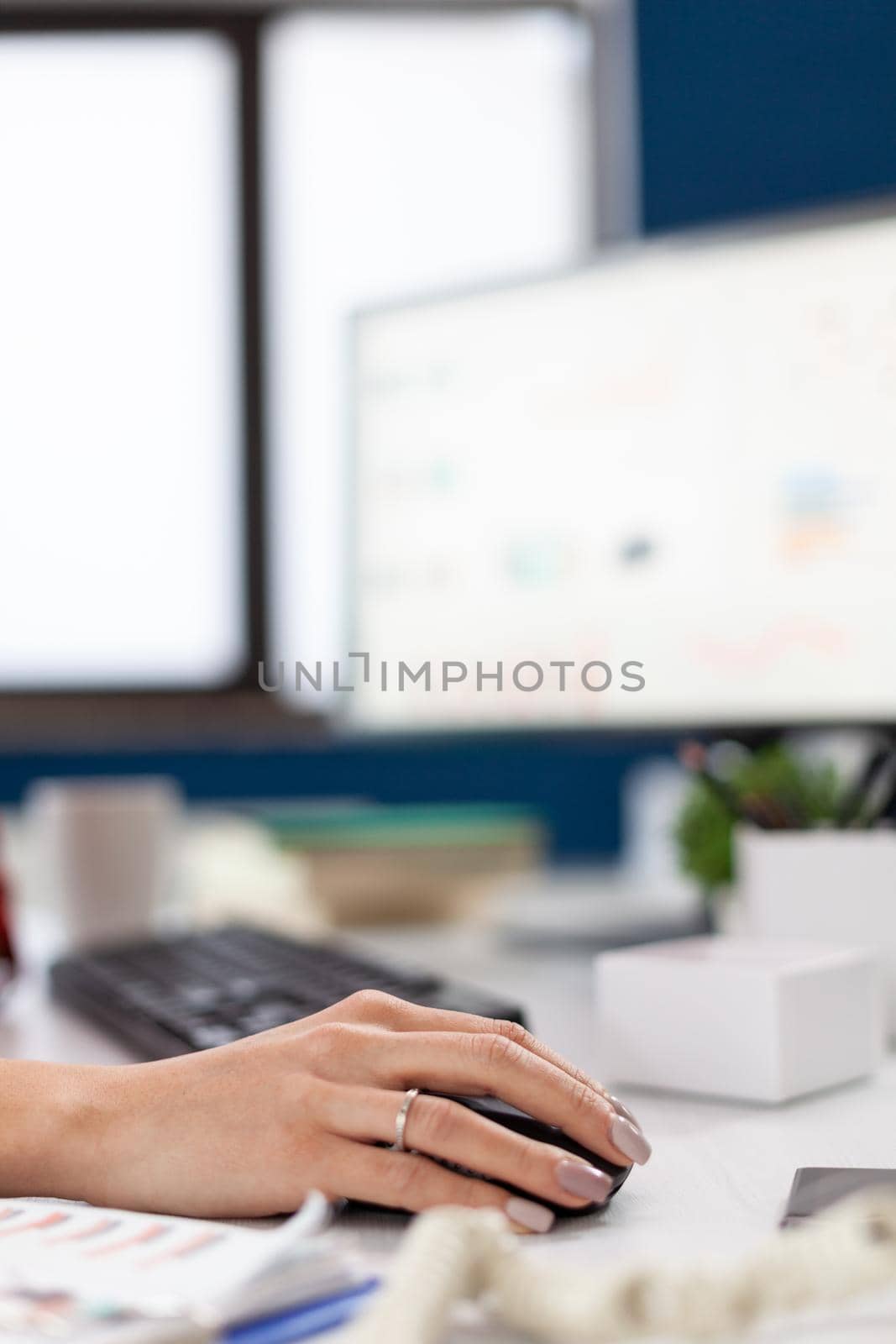 Company executive in his office using and clicking on mouse with bluetooth. Finger of hand pushing on mouse while entrepreneur is reading statistics, on computer screen in workplace .