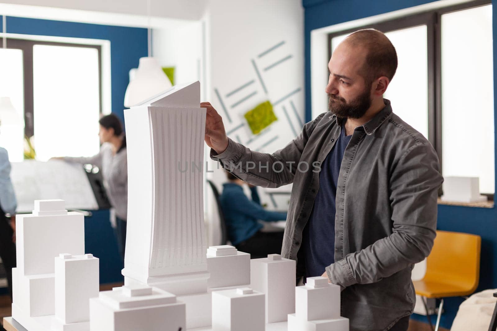 Architect man looking at design in professional office for inspecting maquette building model plan. Caucasian person engineering for modern industrial construction project