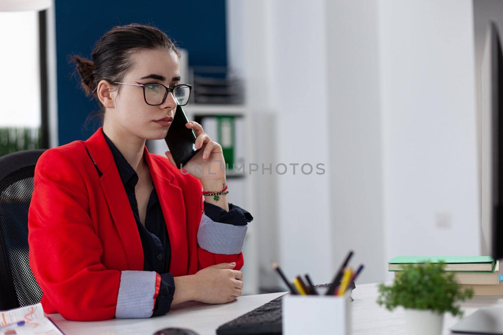 Businesswoman in office workplace privide help consulting client, distantly by mobile phone. Entrepreneur looking at document on computer screen. during phone conversation.