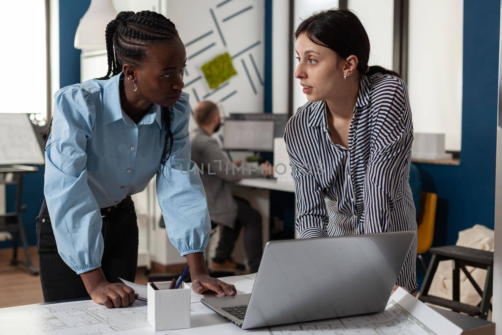 Professional diverse architect women working on laptop by DCStudio
