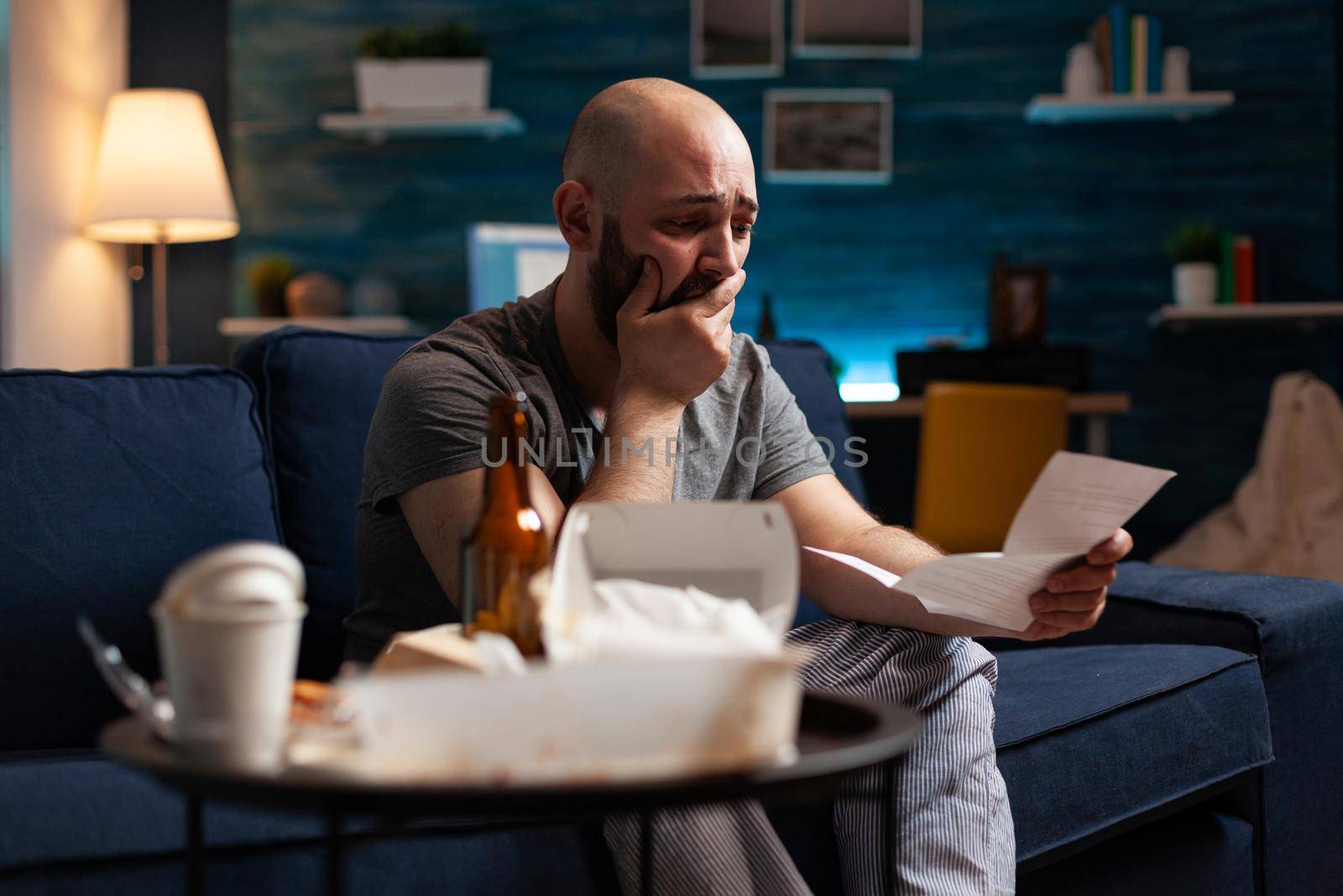 Desperate frustrated stressed young man reading letter, payment debt notification, bad financial report, eviction renter notice. Anxious, worried tenant by warning document for unpaid bank bills