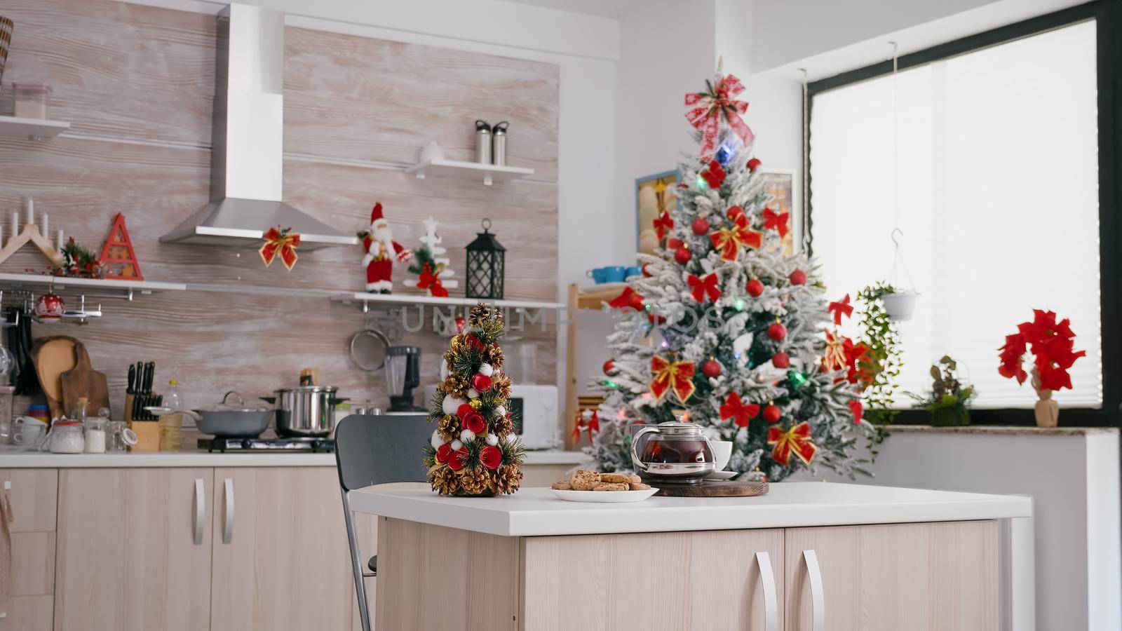 Empty xmas decorated kitchen with nobody in it is ready for christmas morning dessert. On table baked cookie dessert with cup of coffee waiting for guest during winter holidays