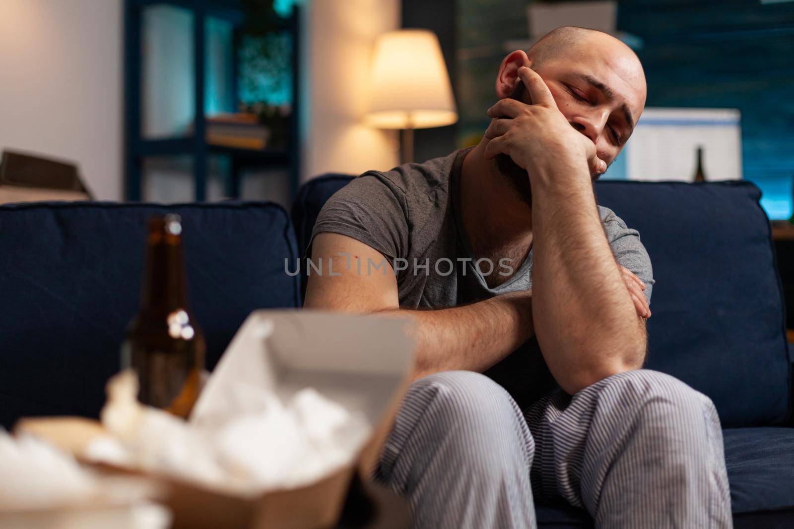 Stressed injured traumatised, frustrated man looking in distance, sitting alone on sofa feeling emotionally unstable, mental desperate, vulnerable suffering from anxiety, chronic disease