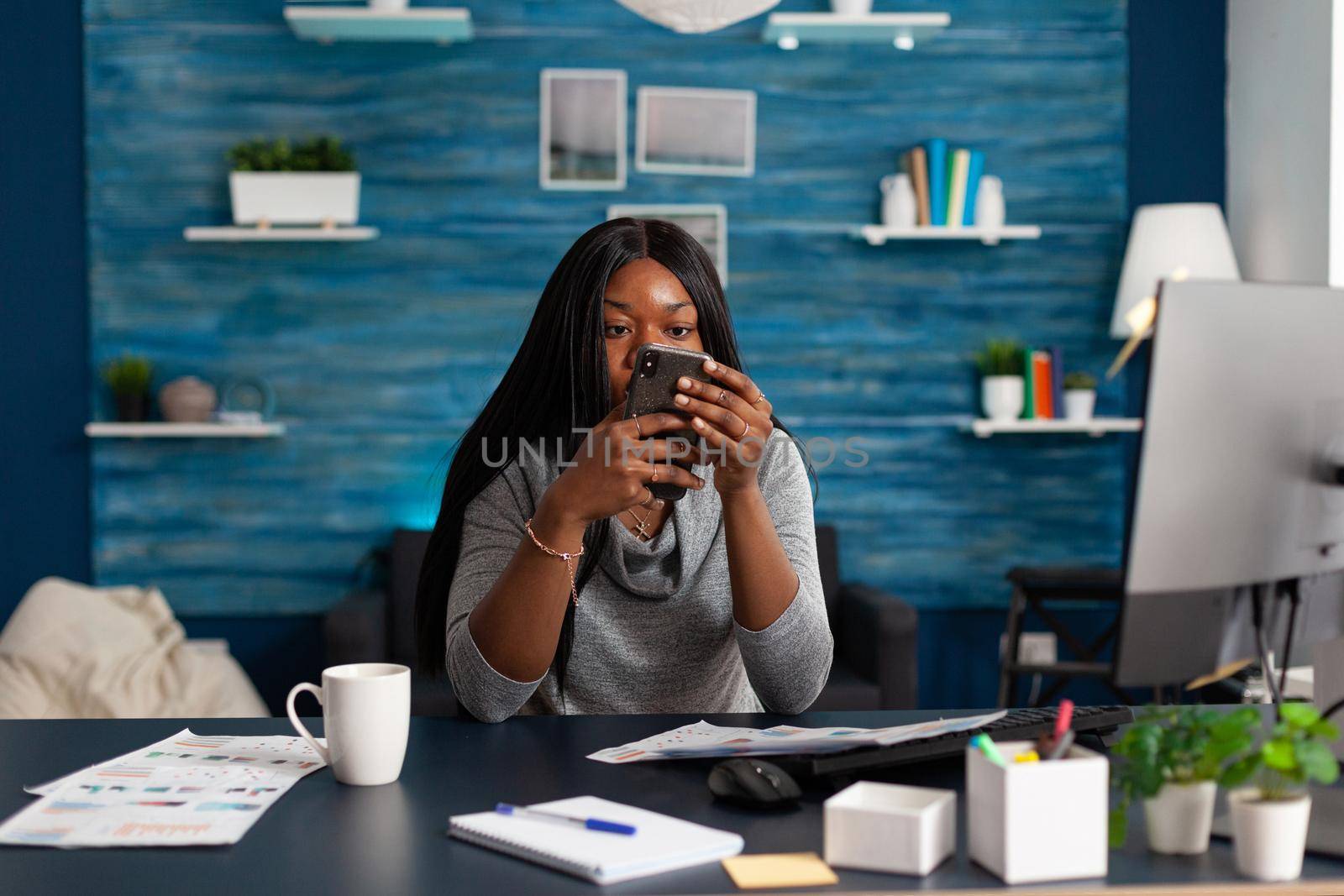 Black student looking into camera while socializing with friends group typing message by DCStudio