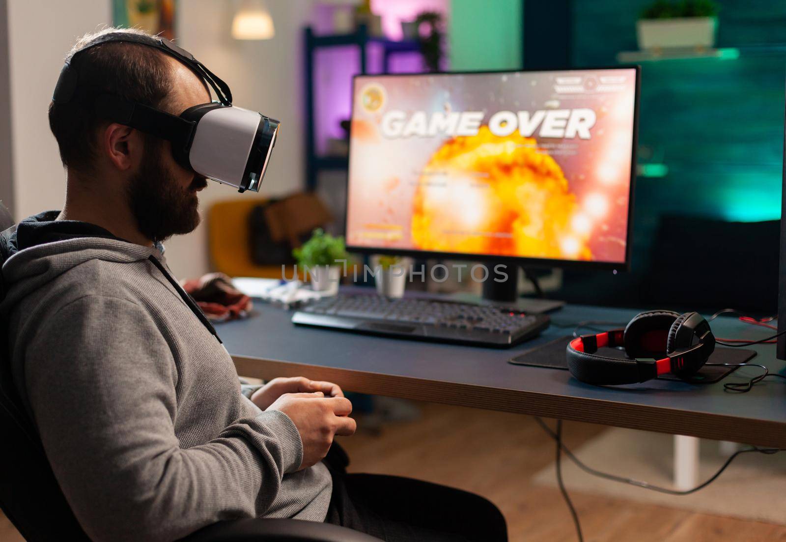 Concentrated gamer wearing virtual reality headset losing space shooter games on online. Defeated player using controller for online competition late at night in gaming room