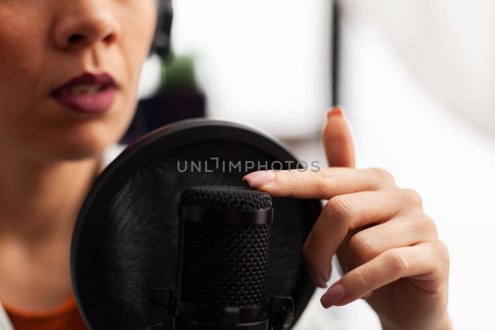 Close up of vlogger tapping microphone before making youtube video. Influencer with recording professional equipment filming herself and having fun using technology to connect with public.