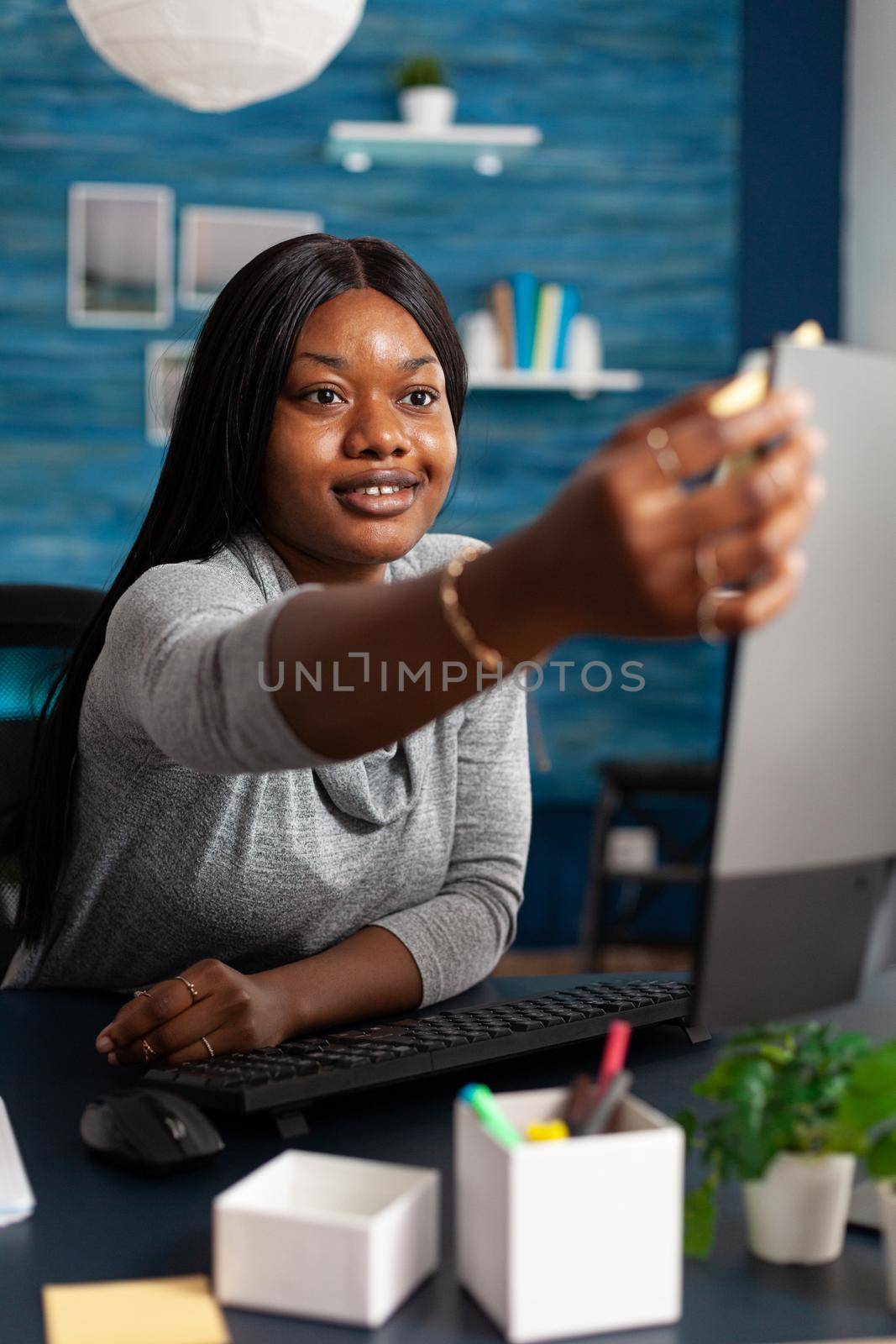 African american student studying business course using university elearning platform working remote from home. Black woman putting stickey notes on computer during academic webinar