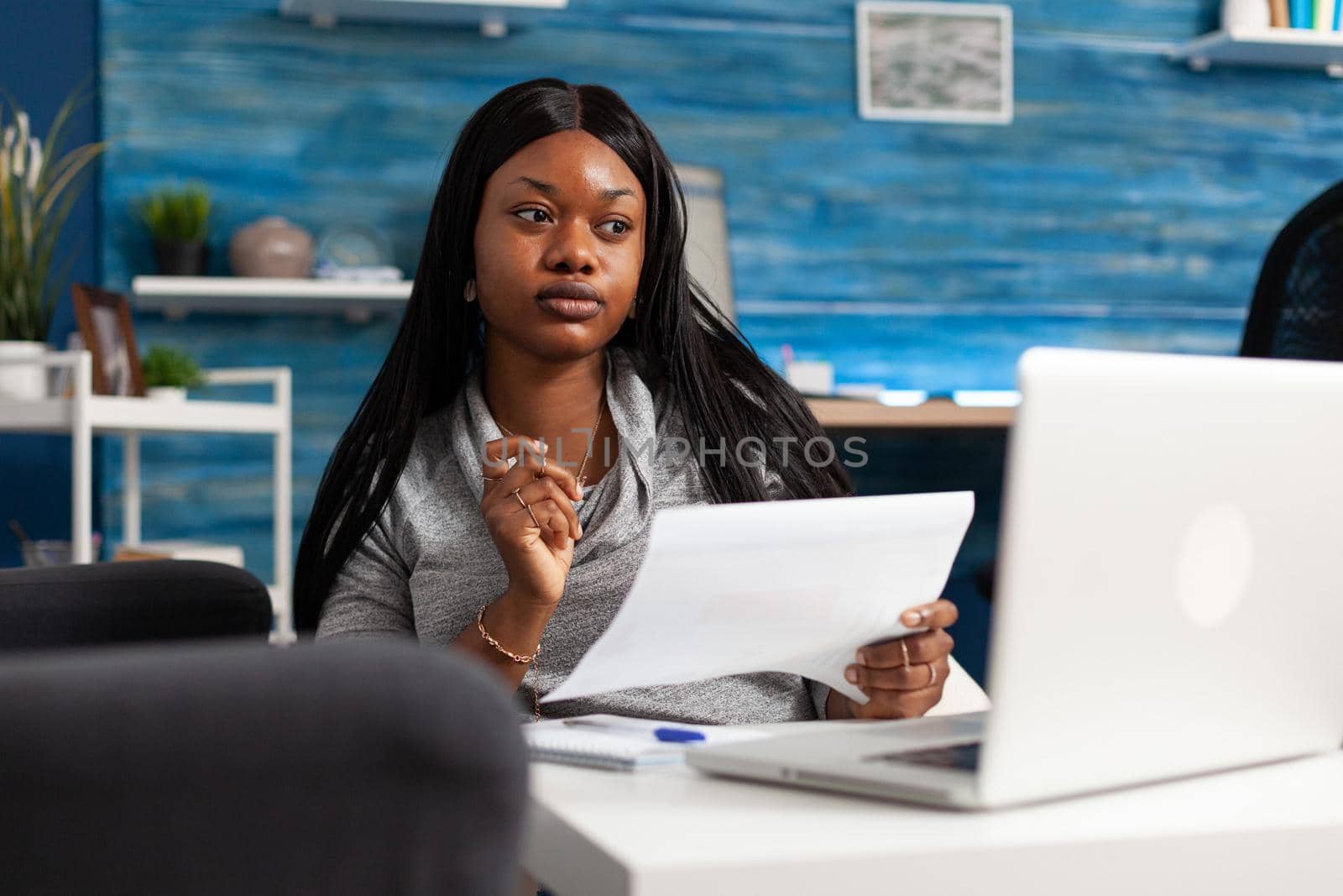 Black woman looking at accounting strategy on monitor using laptop computer remote working at financial graph planning presentation. African american student analyzing infographics document at home