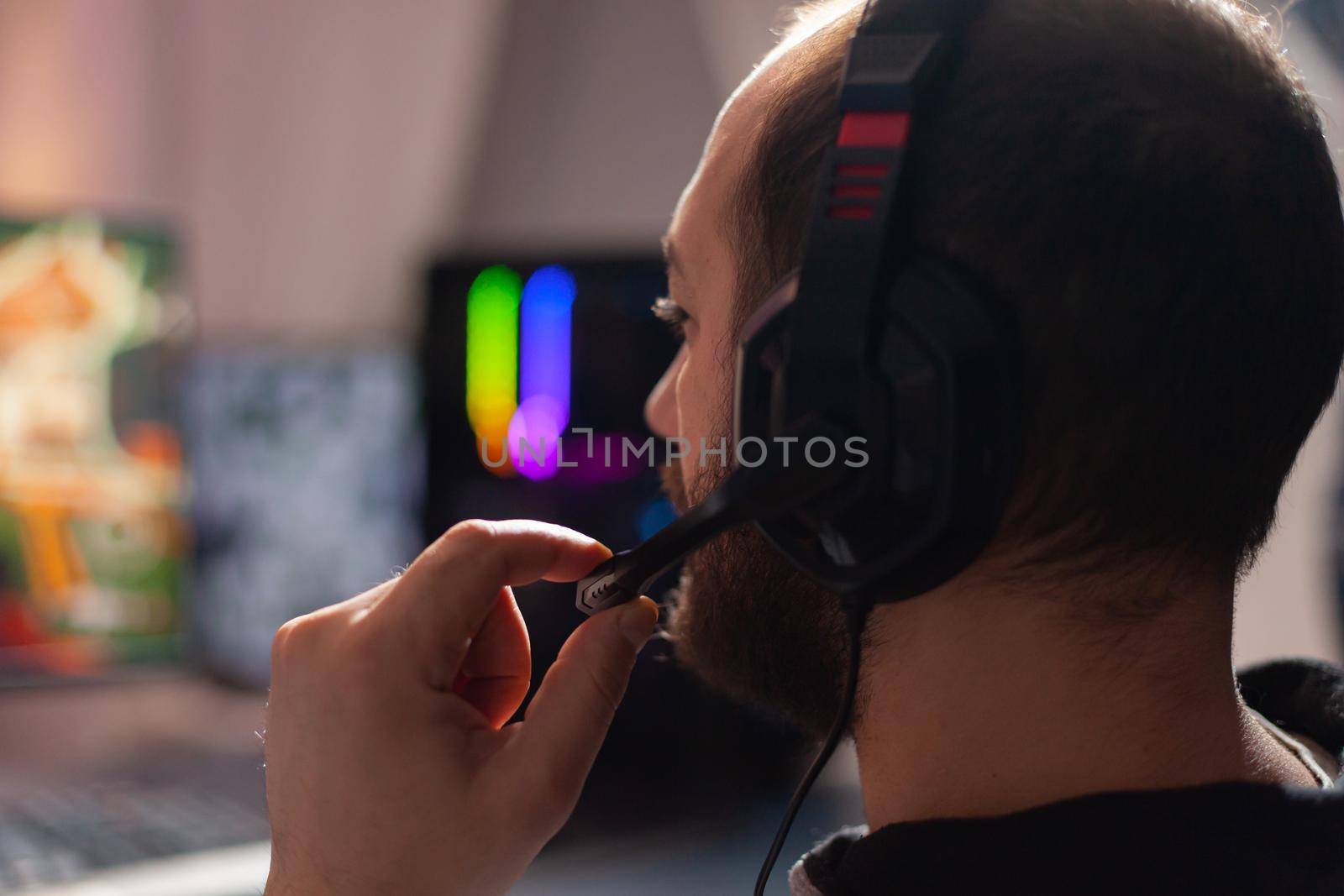 Close up portrait of pro esport player talking on headset with his teammates during online gaming virtual tournament. Home studio room with RGB neon lights, digital player