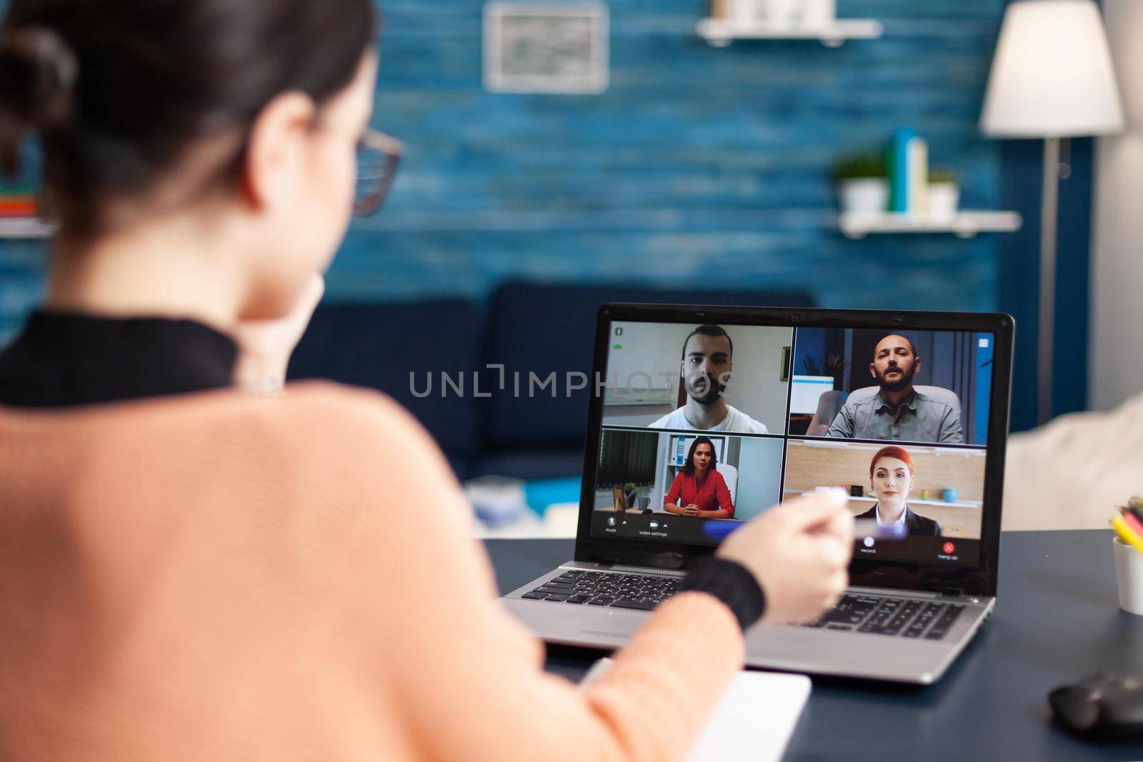 Student discussing about univeristy education looking at online meeting using laptop computer. Young woman having remote education sitting in living room during coronavirus quarantine