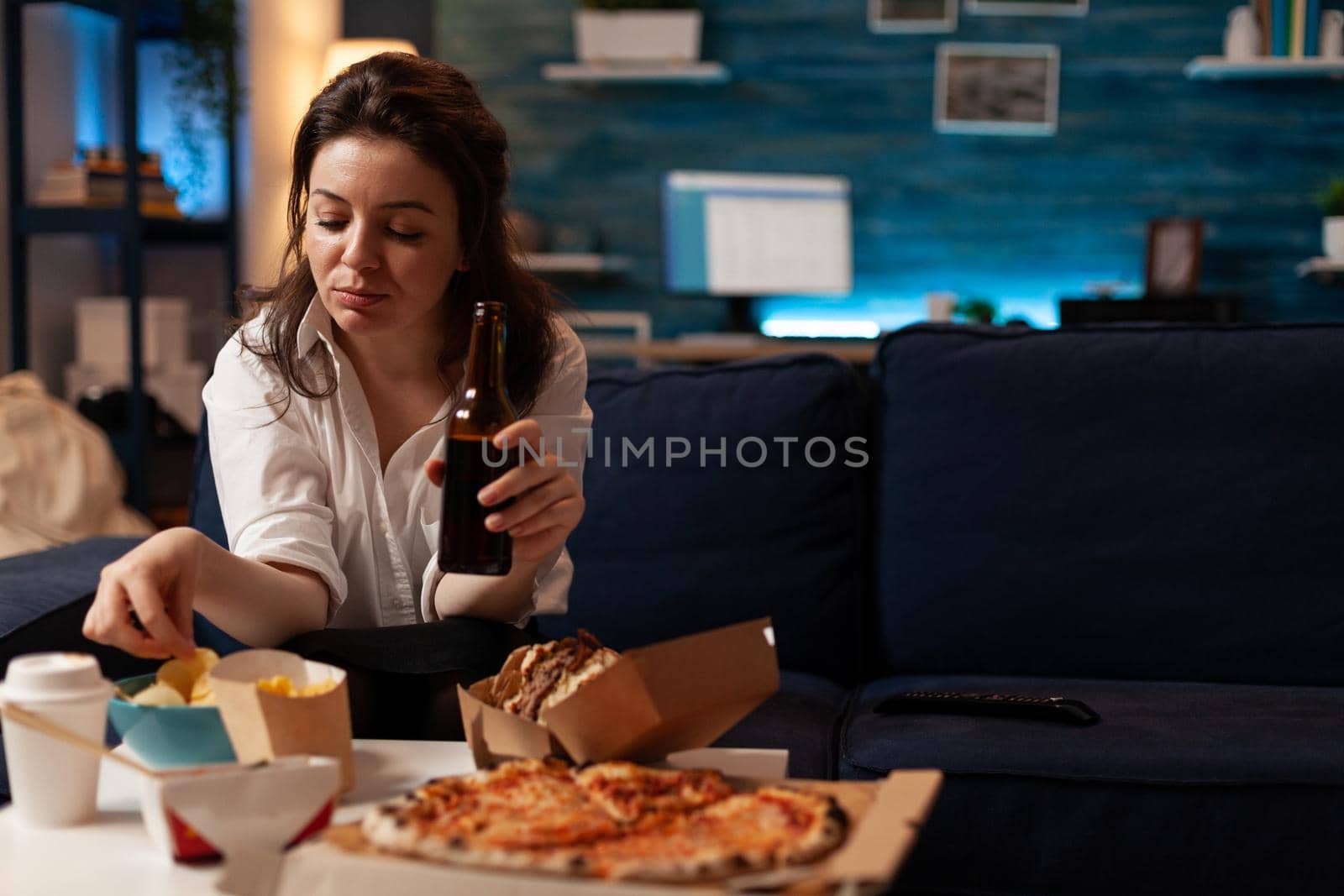 Happy woman sitting on sofa watching comedy movie film on television in evening eating tasty delicious snack. Caucasian female enjoying takeaway food home delivered. Junck-food lunch order