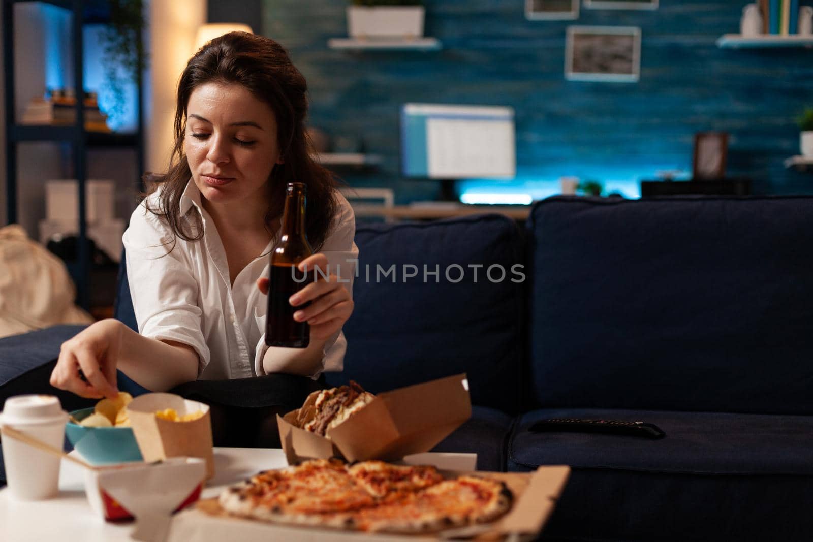 Happy woman sitting on sofa watching comedy movie film on television in evening by DCStudio