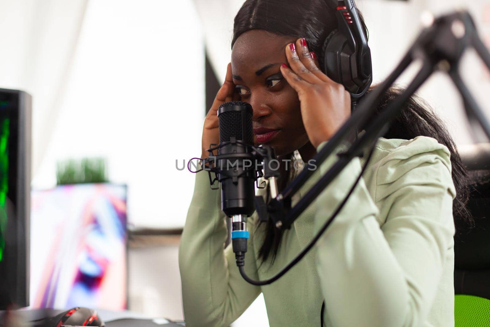 Afro virtual game player looking disappointed after losing space shooter championship. Professional gamer streaming online video games with new graphics on powerful computer.