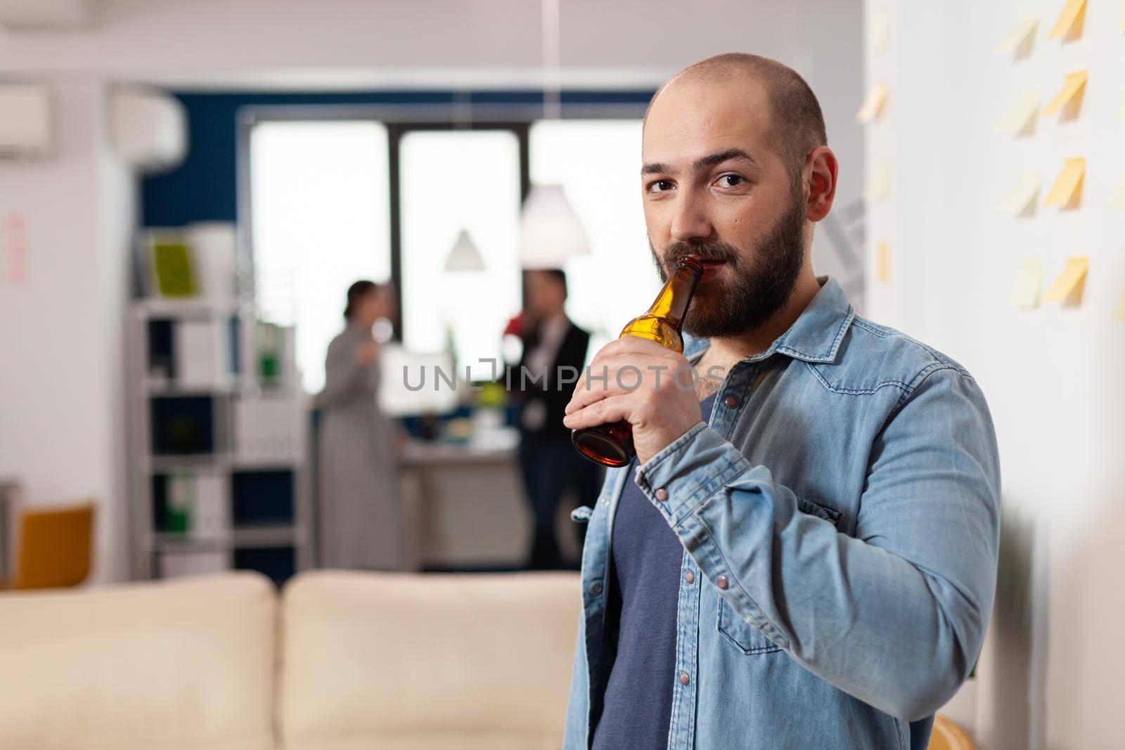 Man drinking bottle of beer after work meeting by DCStudio