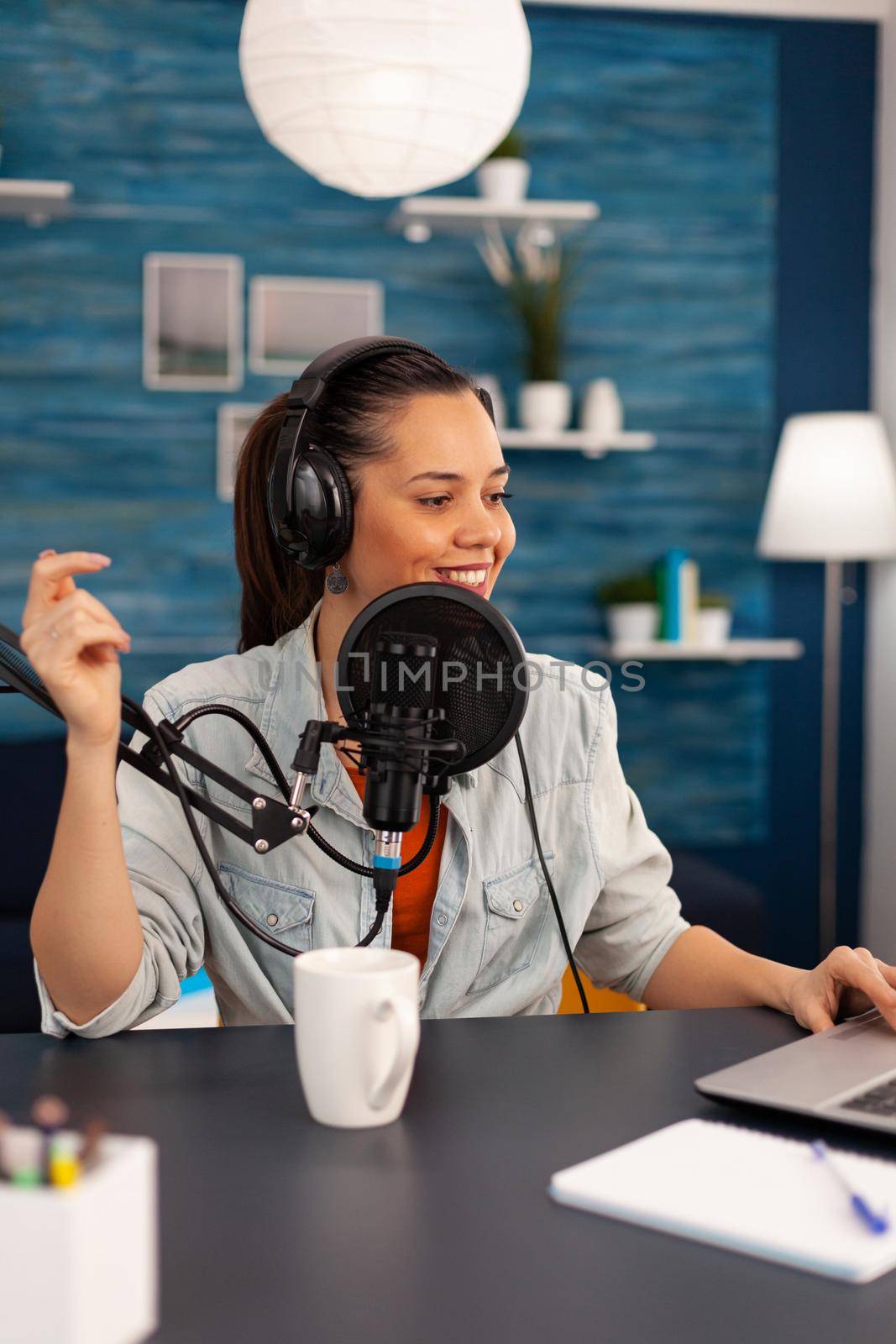 Vlogger looking at laptop while asking her audience to subscribe on her youtube channel. Digital influcencer recording talk show using modern equipment in home studio podcast