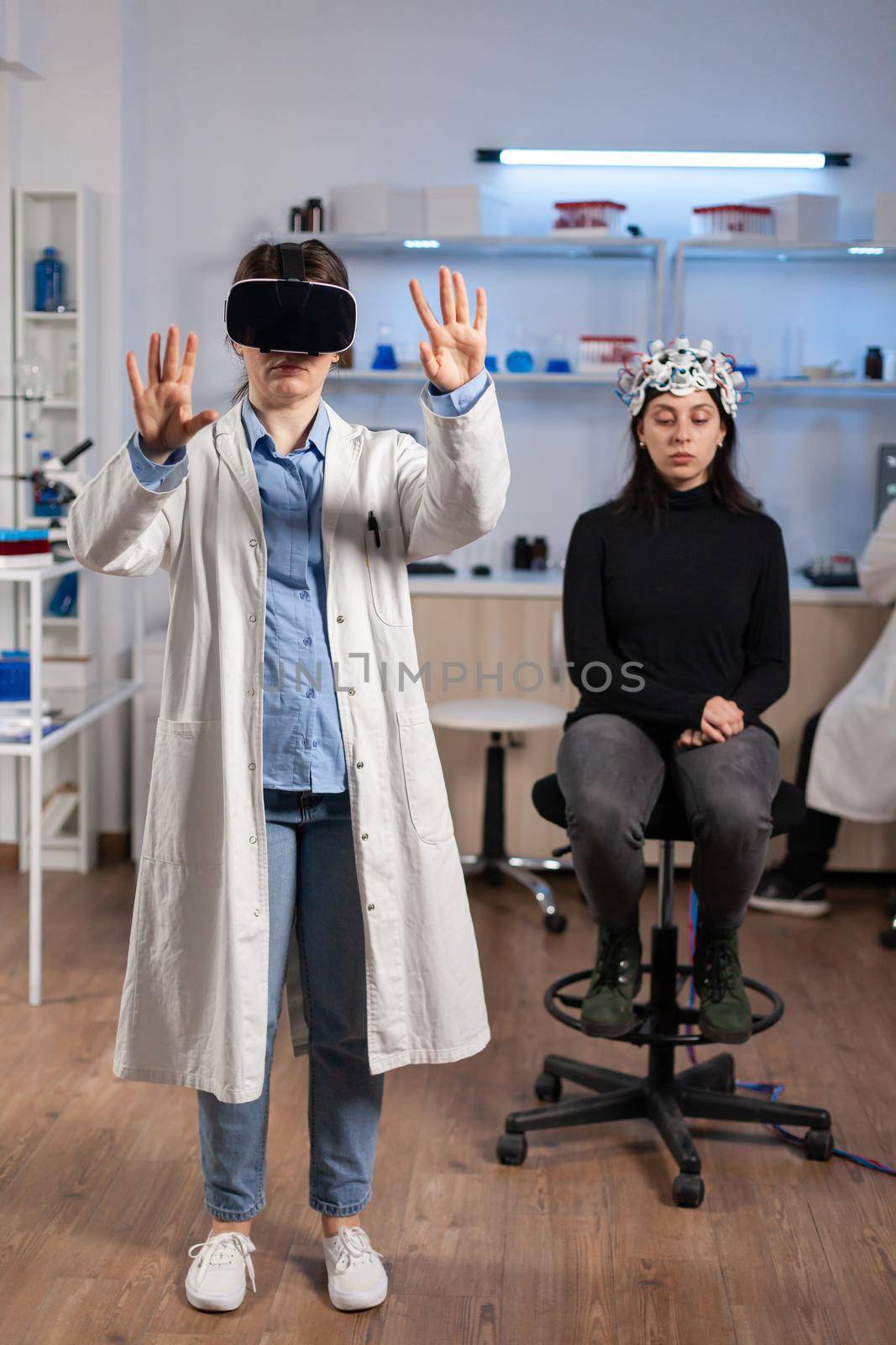 Neuroscience doctor gesturing wearing vr goggles during brain science research, patient with neurology scanner in laboratory. Doctor searching diagnosis, experiment , eeg , medicine lab.