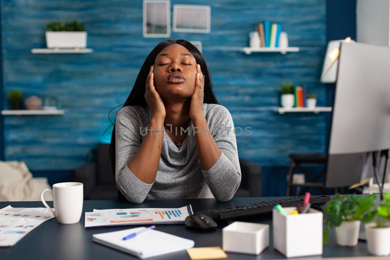 Worried displeased african student suffering headache migraine sitting at desk table in living room. Disappointment frustration sick upset black woman having forehead pain during lockdown