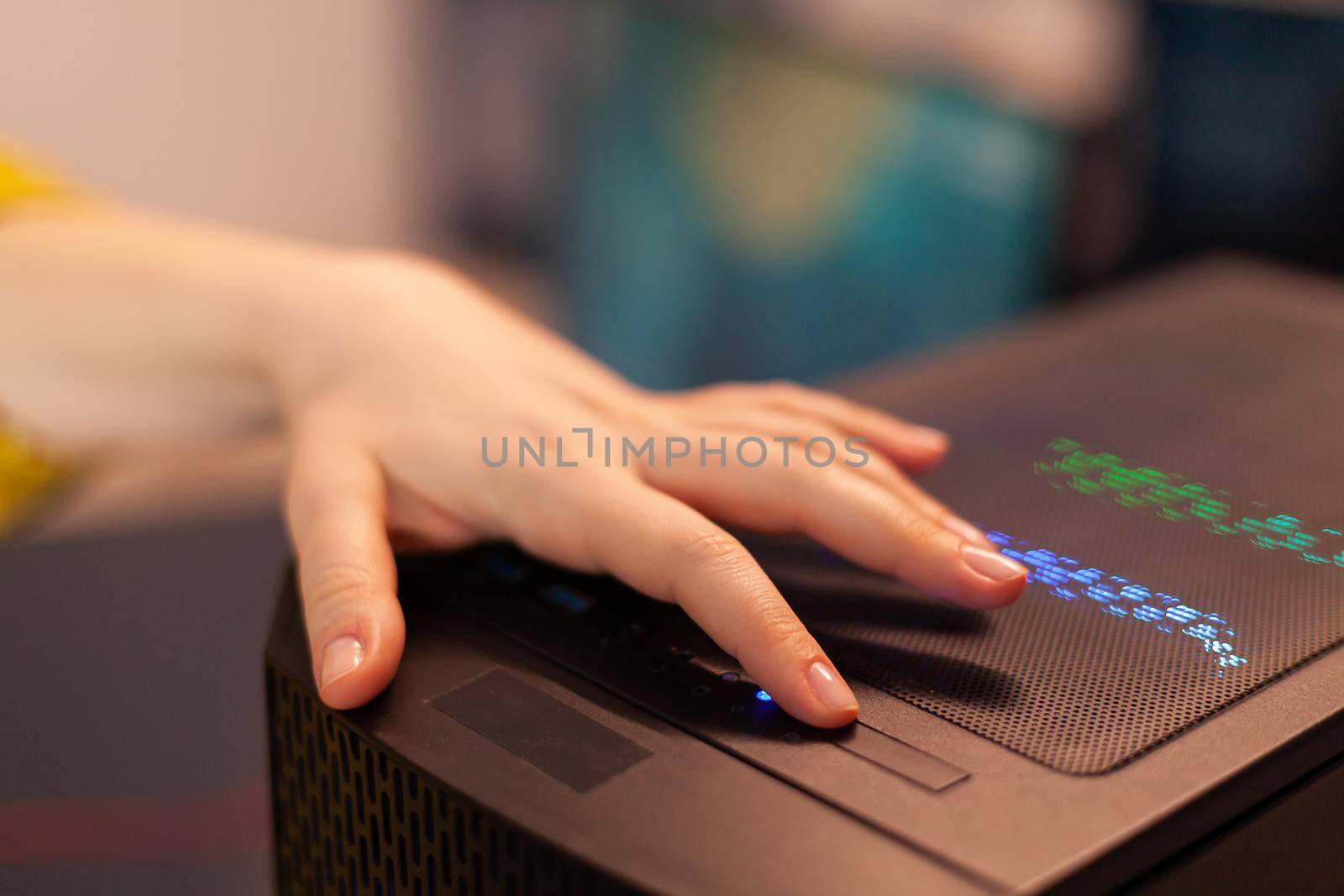 Woman gamer power on computer unit preparing for gaming tournament. Cyber performing on powerful personal computer in stylish room starting to play online shooter game.