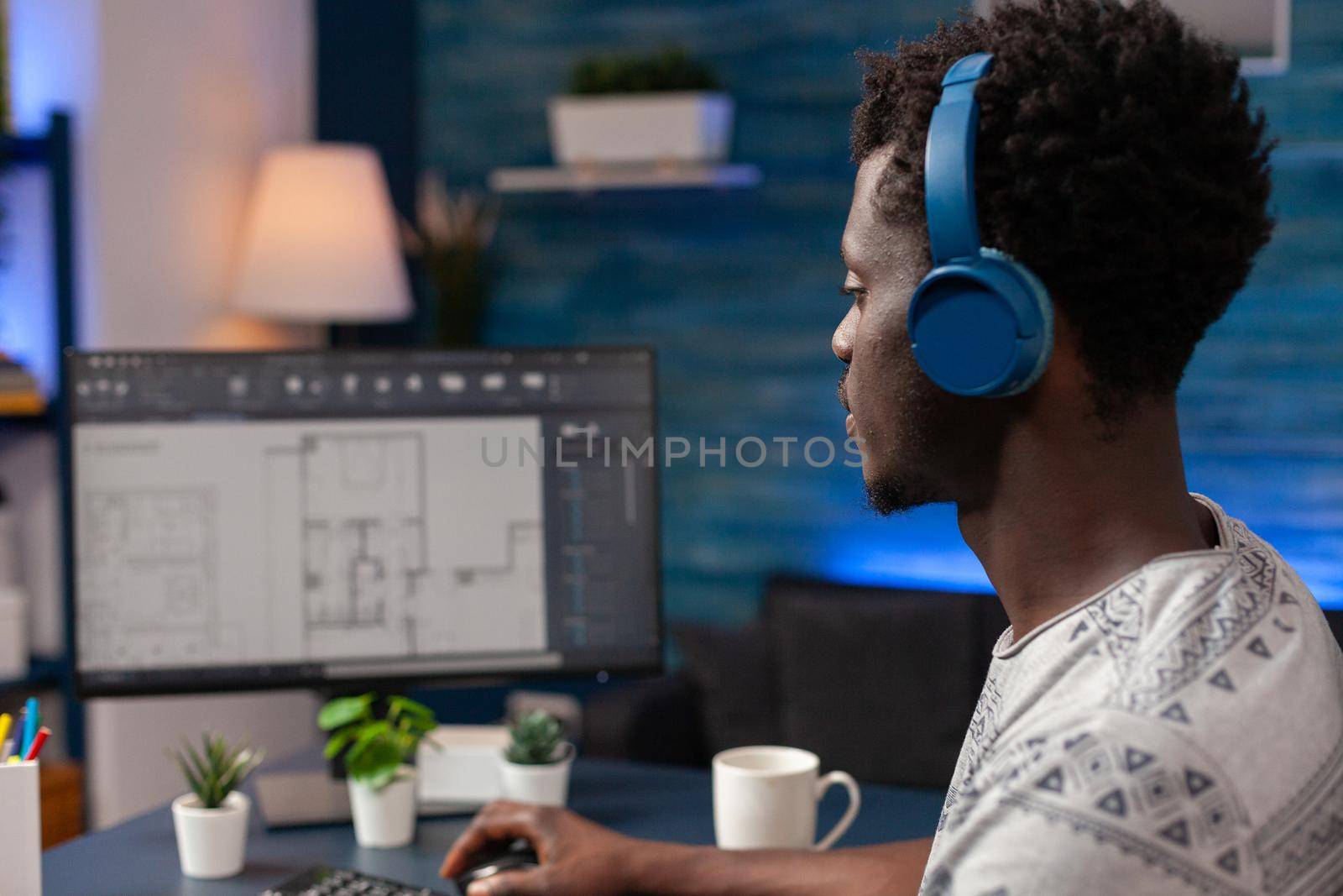 African american architect worker with headset sitting at desk in living room by DCStudio