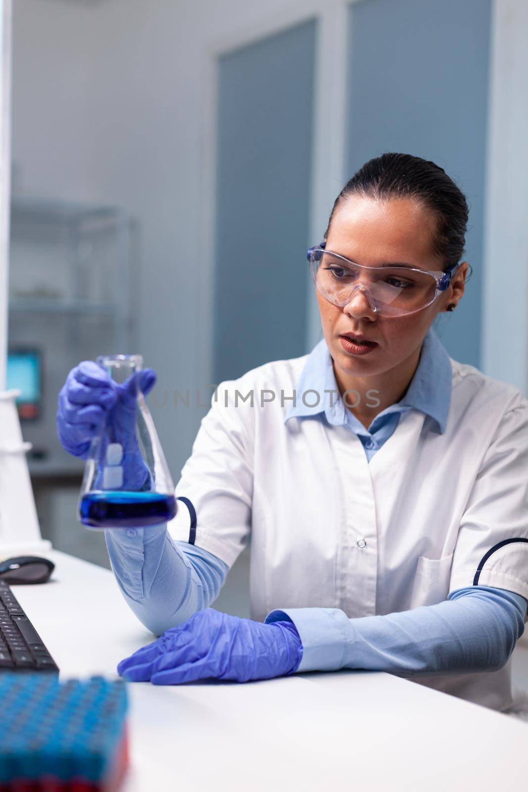 Chemist researcher working at microbiology scientific experiment in biochemistry pharmaceutical hospital laboratory. Scientist woman doctor analyzing liquid solution results using medical glass flask