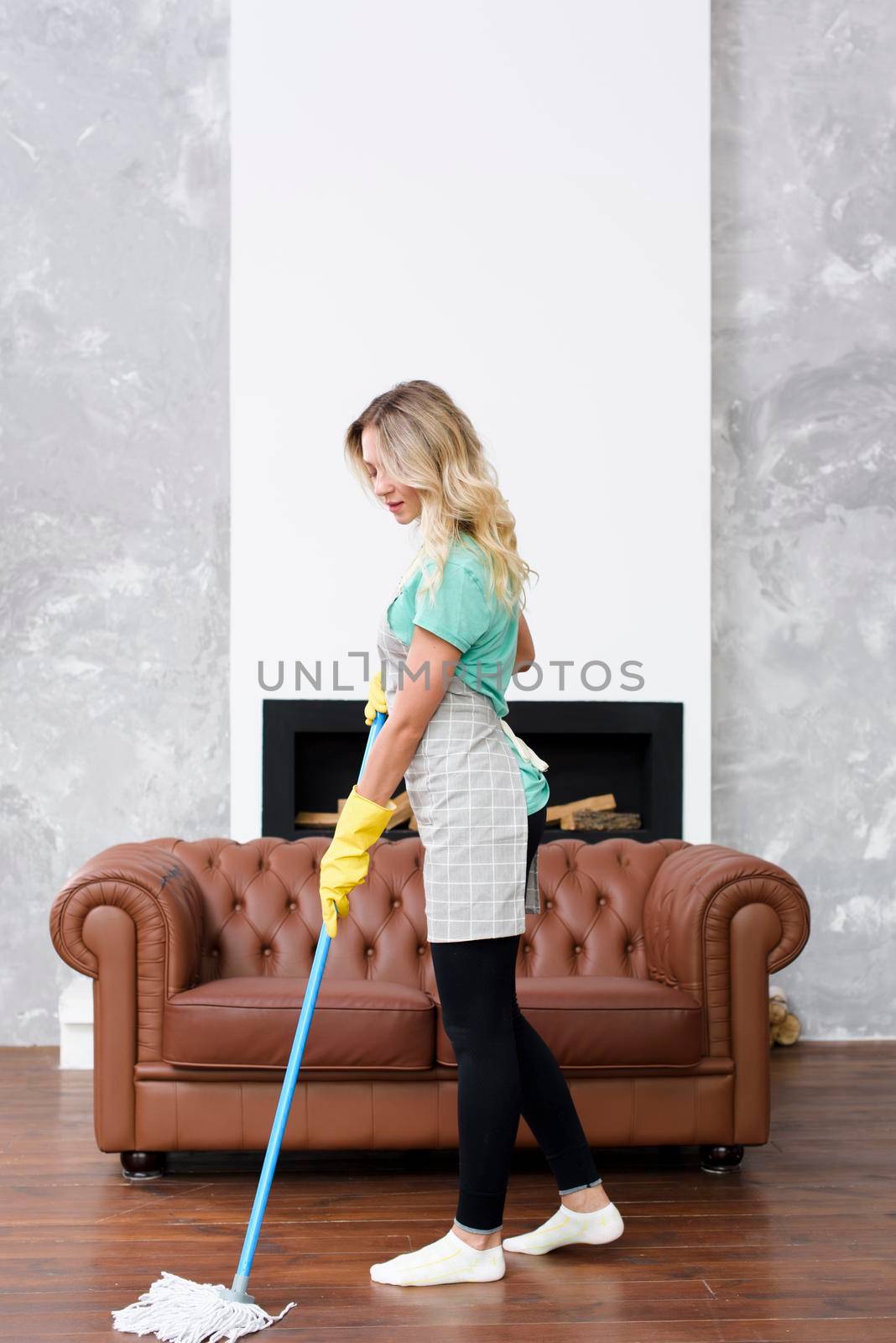 blonde female housekeeper wiping floor mop home. High quality photo by Zahard