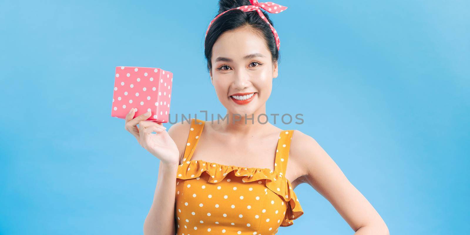 Happy pretty woman in dress holding little box isolated on a blue background by makidotvn