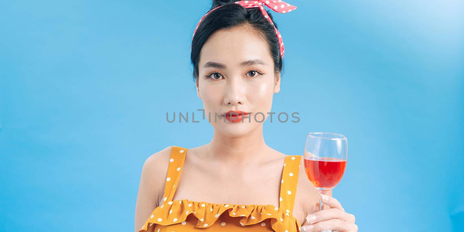 Portrait of a cheerful young woman dressed in yellow dress holding glass of champagne