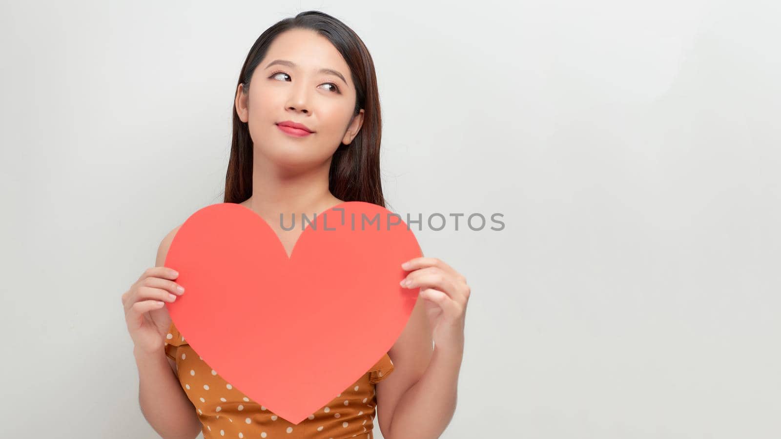 Attractive young smiling woman holding big red heart in hands isolated on white background.  by makidotvn