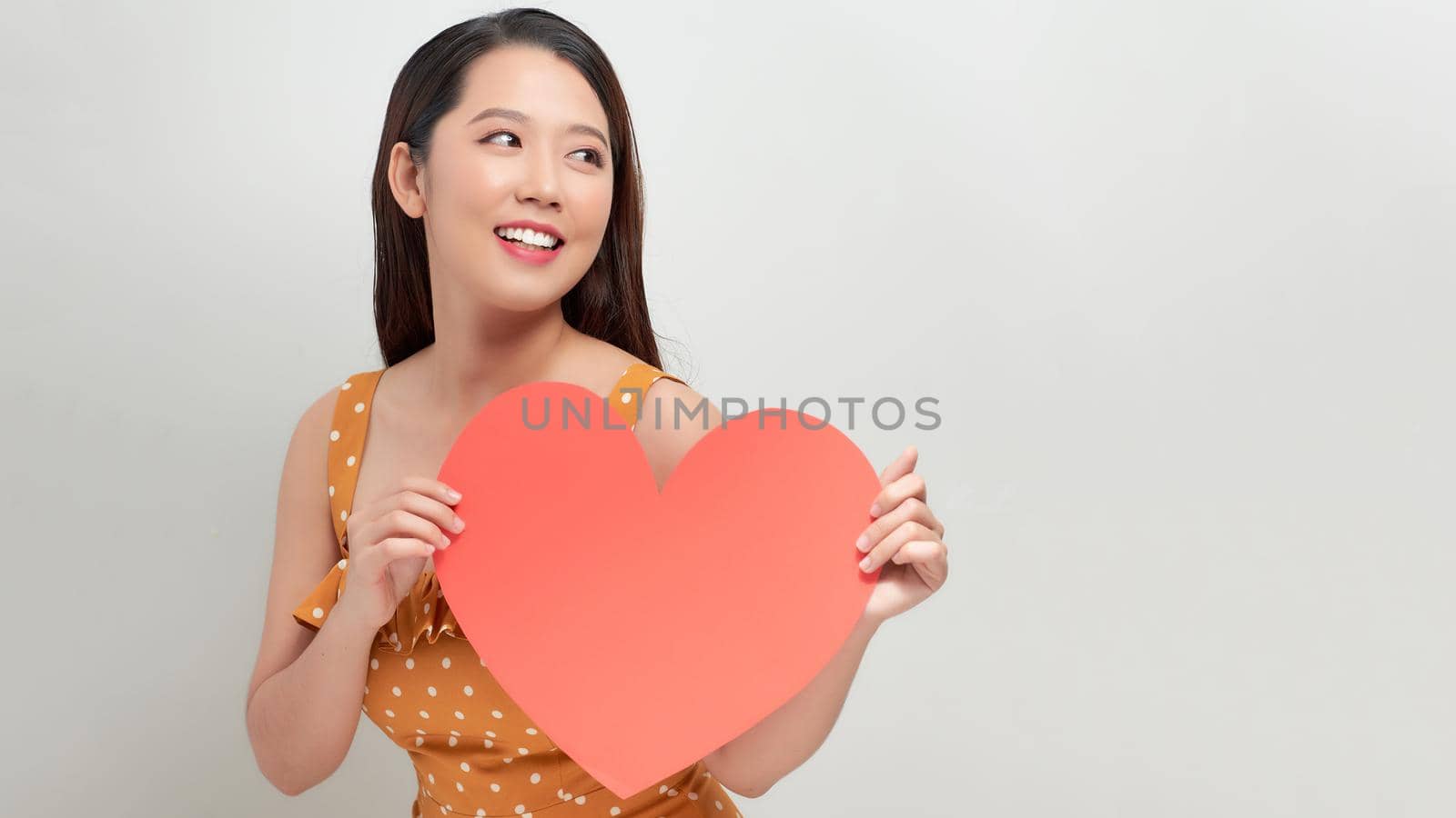 Woman holding big red heart on white background