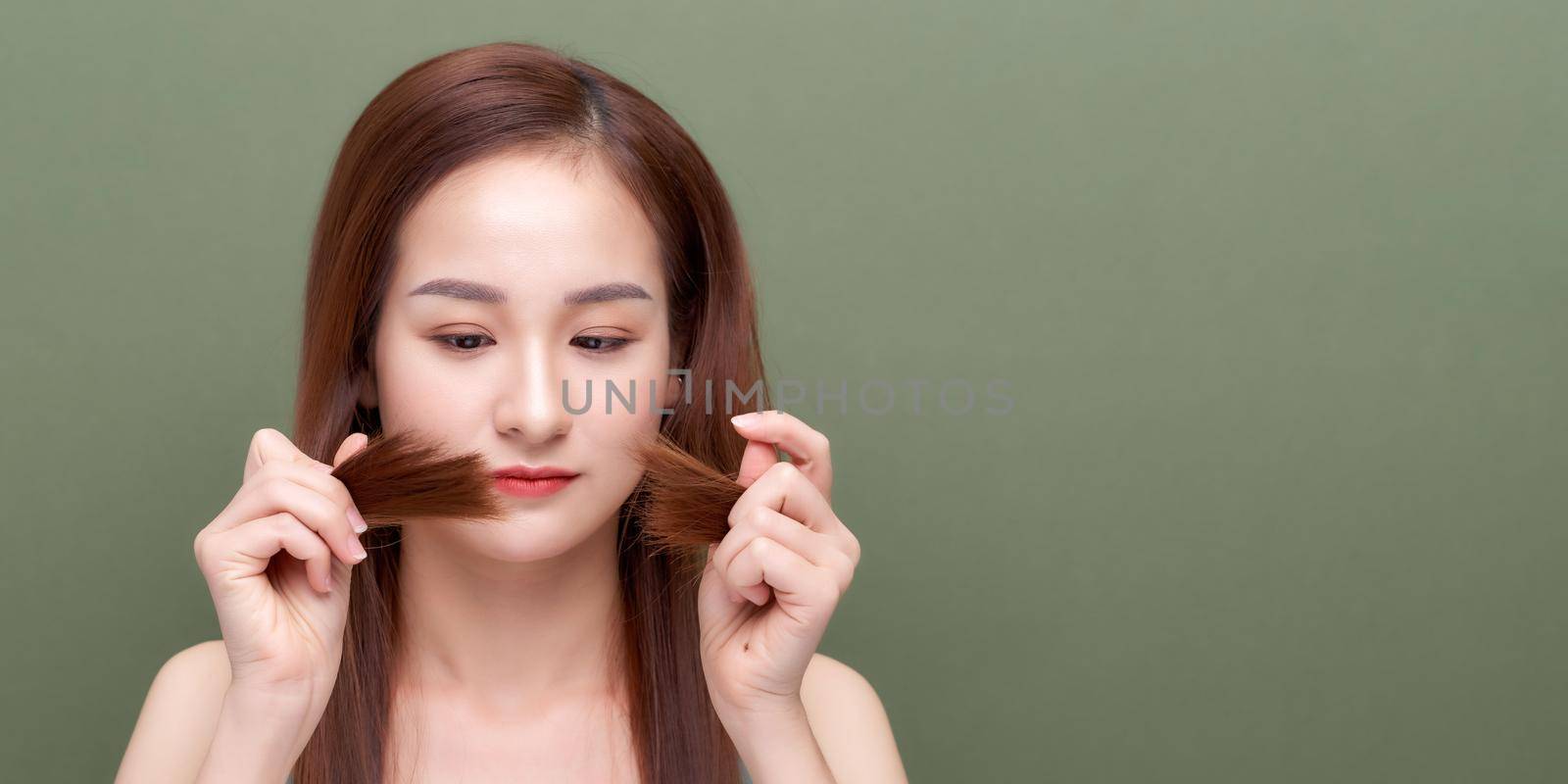 Woman holding damaged hair the hand and looking