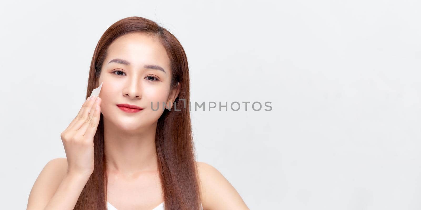 Woman removing makeup, holds cotton pads near face