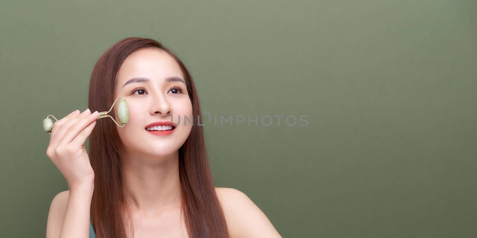 Young woman applying jade roller face massage
