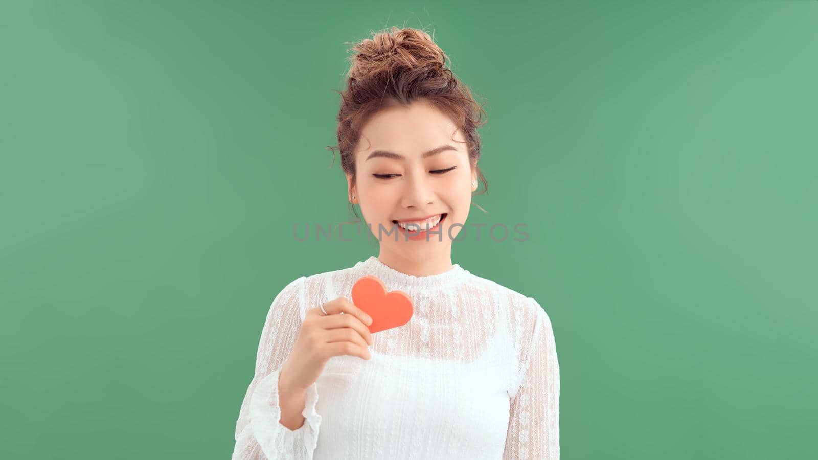 Beautiful young woman with red heart on color background