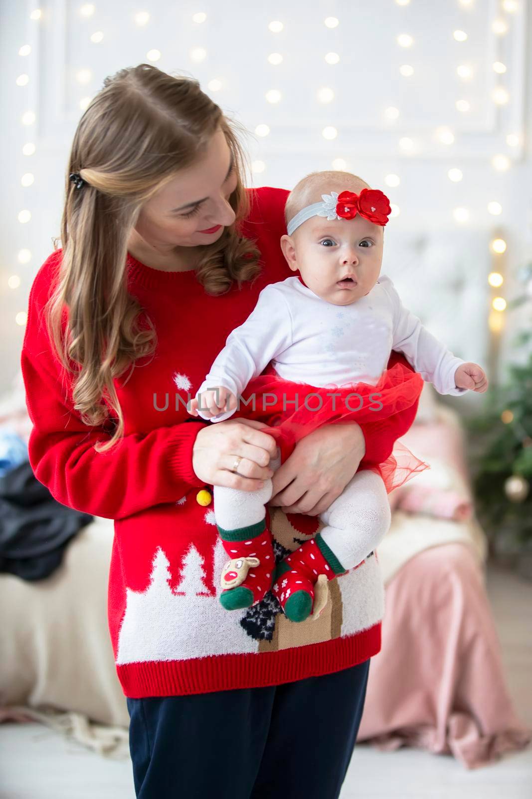 Mom and child at Christmas. A young woman with a newborn daughter on the background of Christmas interiors.