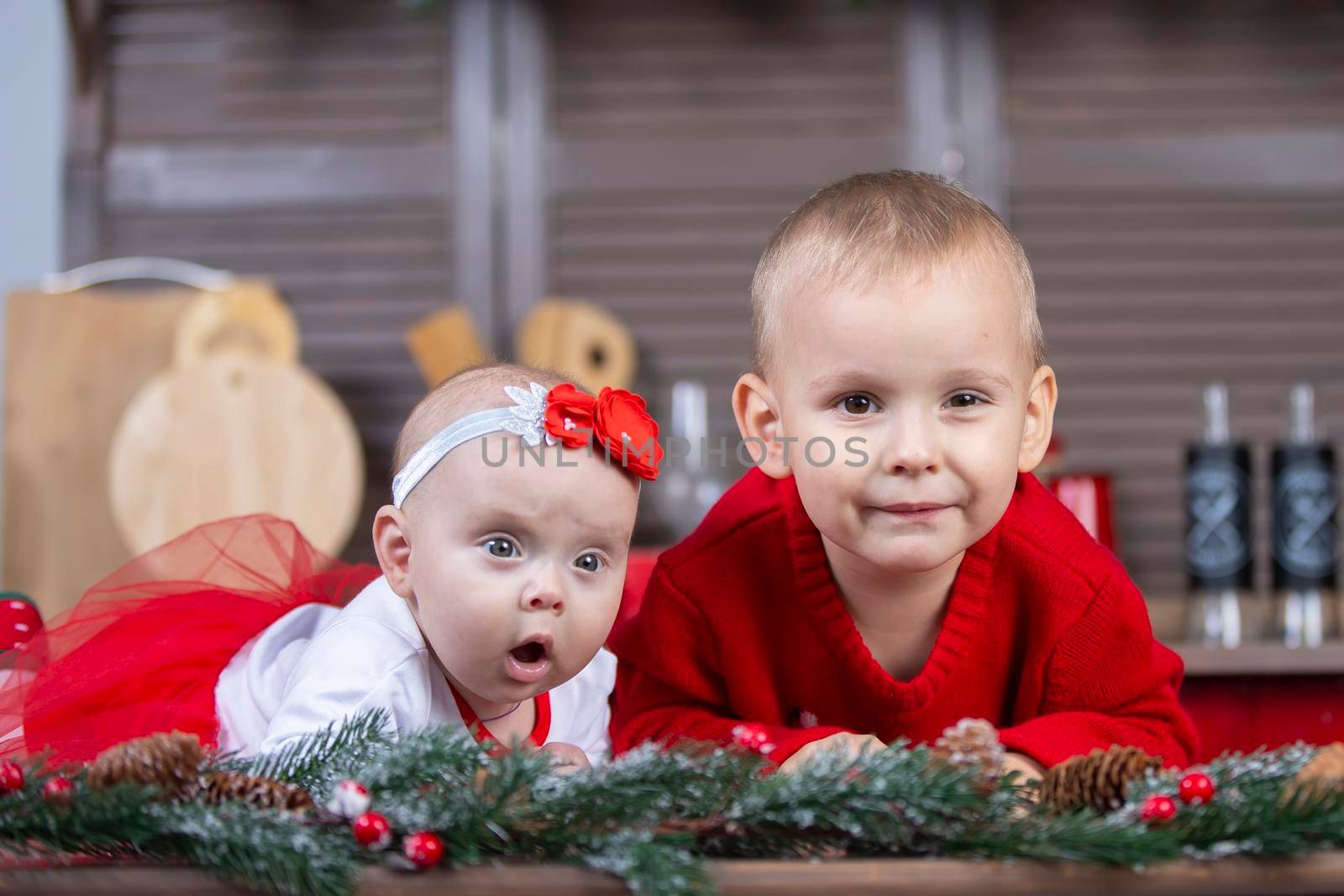 Little brother and newborn sister in a Christmas interior. Funny little children with Christmas decorations.