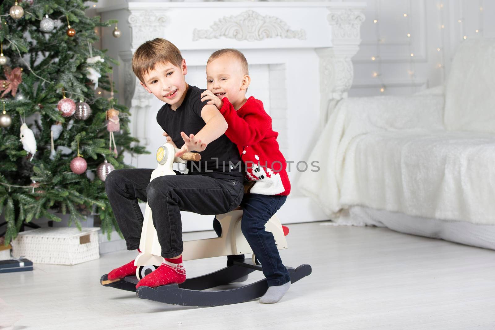 Children play in the Christmas room. Two brothers elder and younger in New Year's decorations.