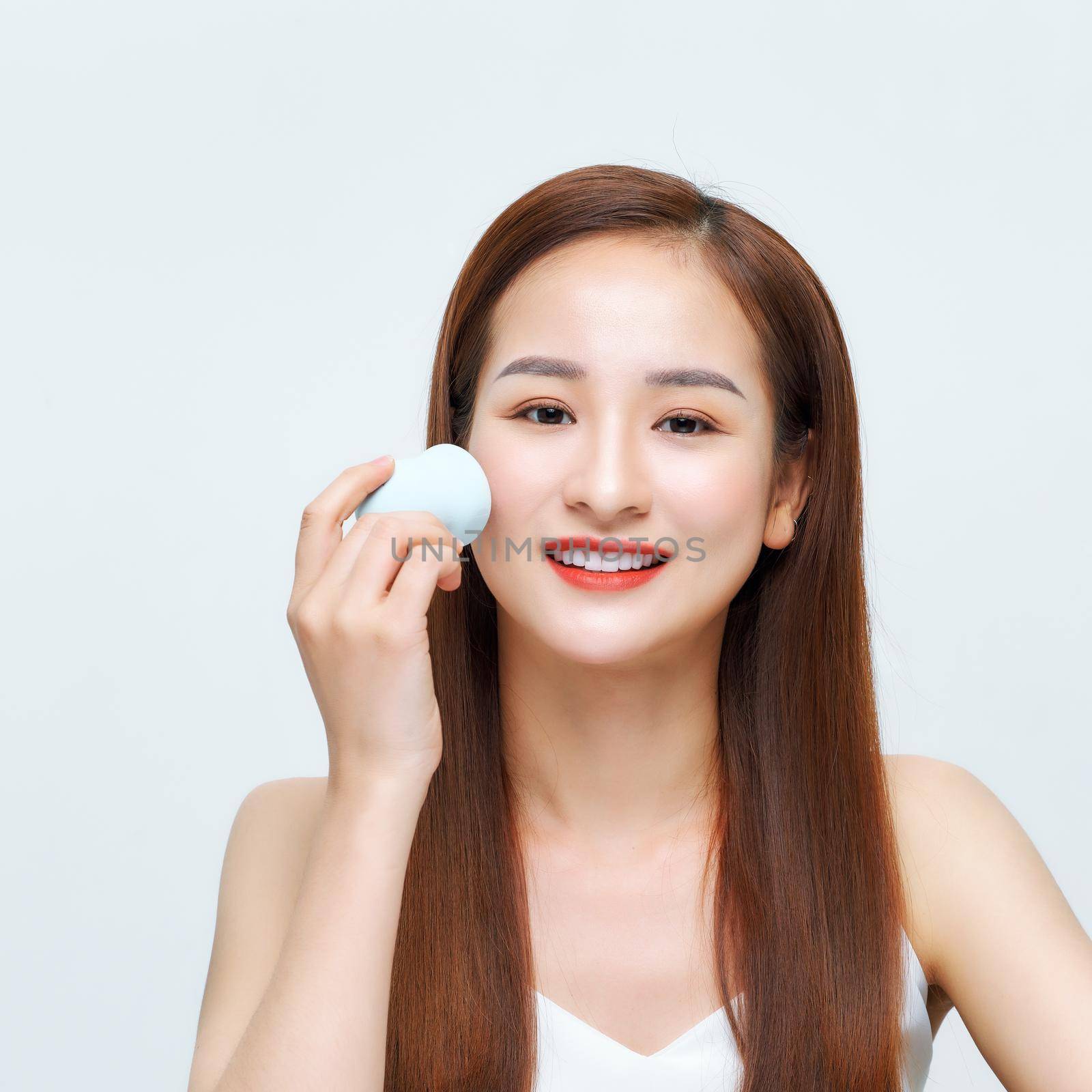 Beautiful girl applying foundation with sponge by makidotvn