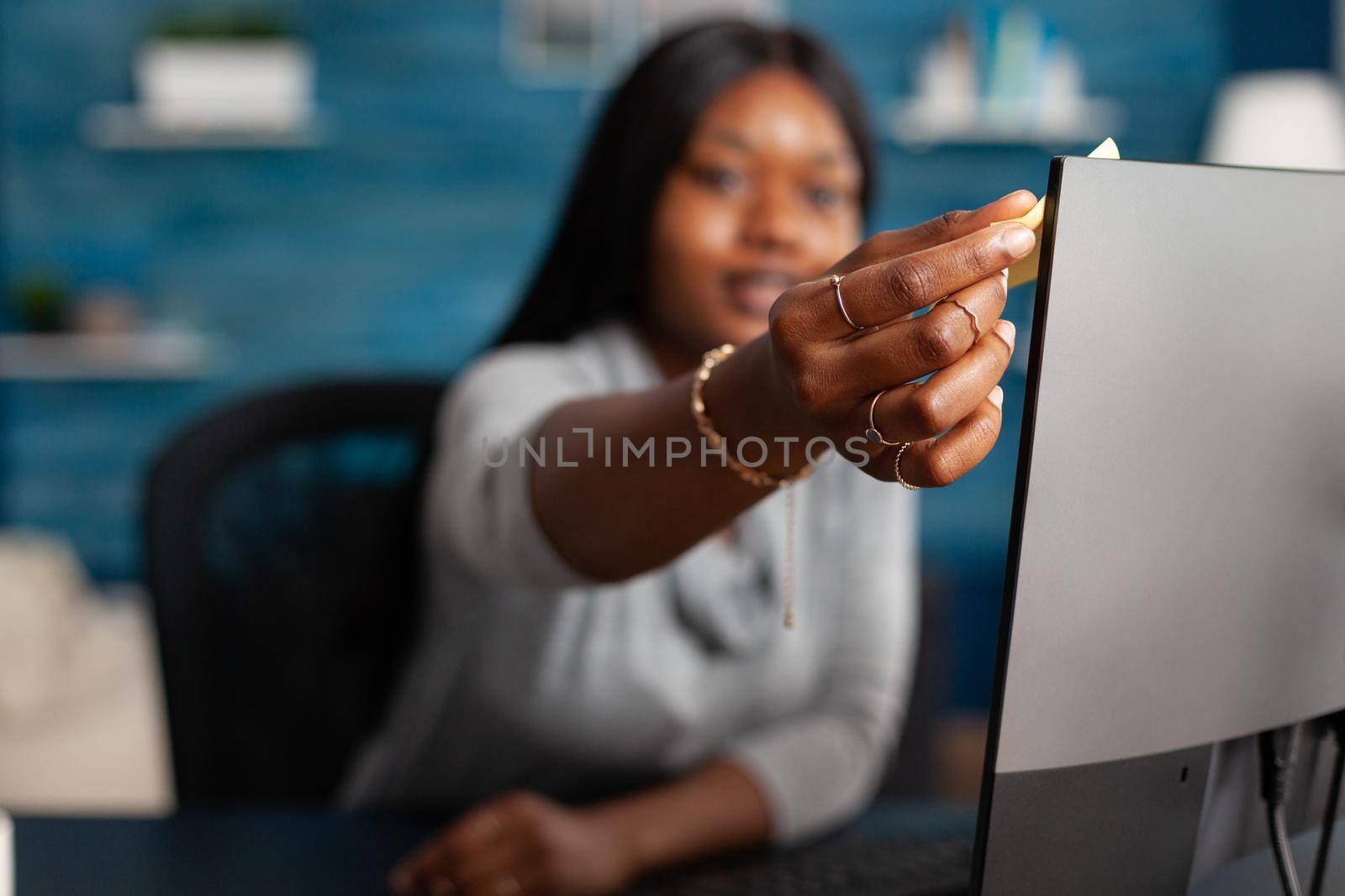 African american student putting stickey notes on computer working remote from home at communication lesson. Woman with dark skin studying math academic lesson using elearning platform