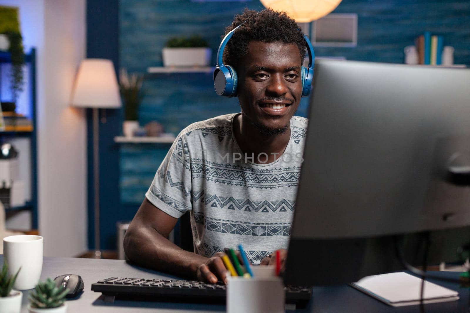 African american employee using computer for remote work typing marketing ideas on keyboard. Businessman with headphones working from home with online technology . and networking.