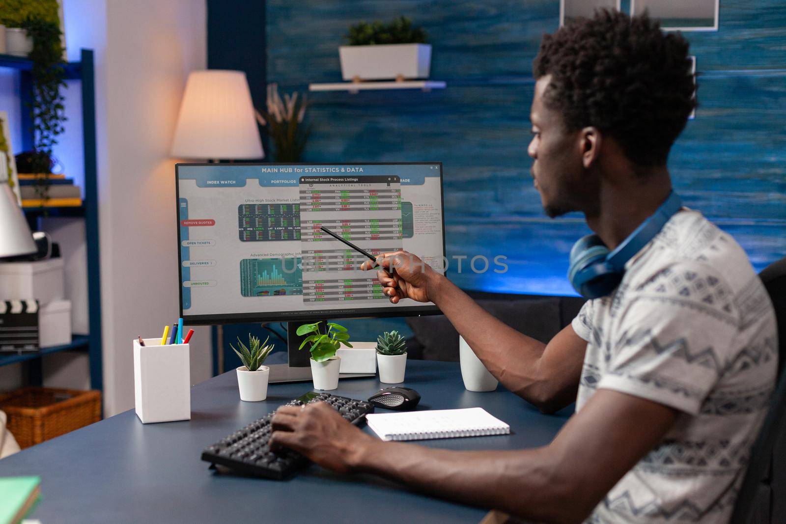 African american borker pointing at digital crypto investment analyzing stock market value working remote from home. Young trader checking trading strategy. Currency data charts on computer screen.