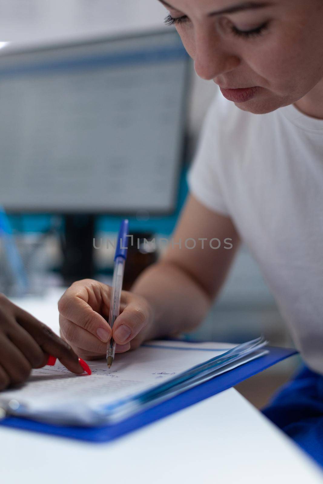 Closeup of woman patient signing medical questionnaire by DCStudio