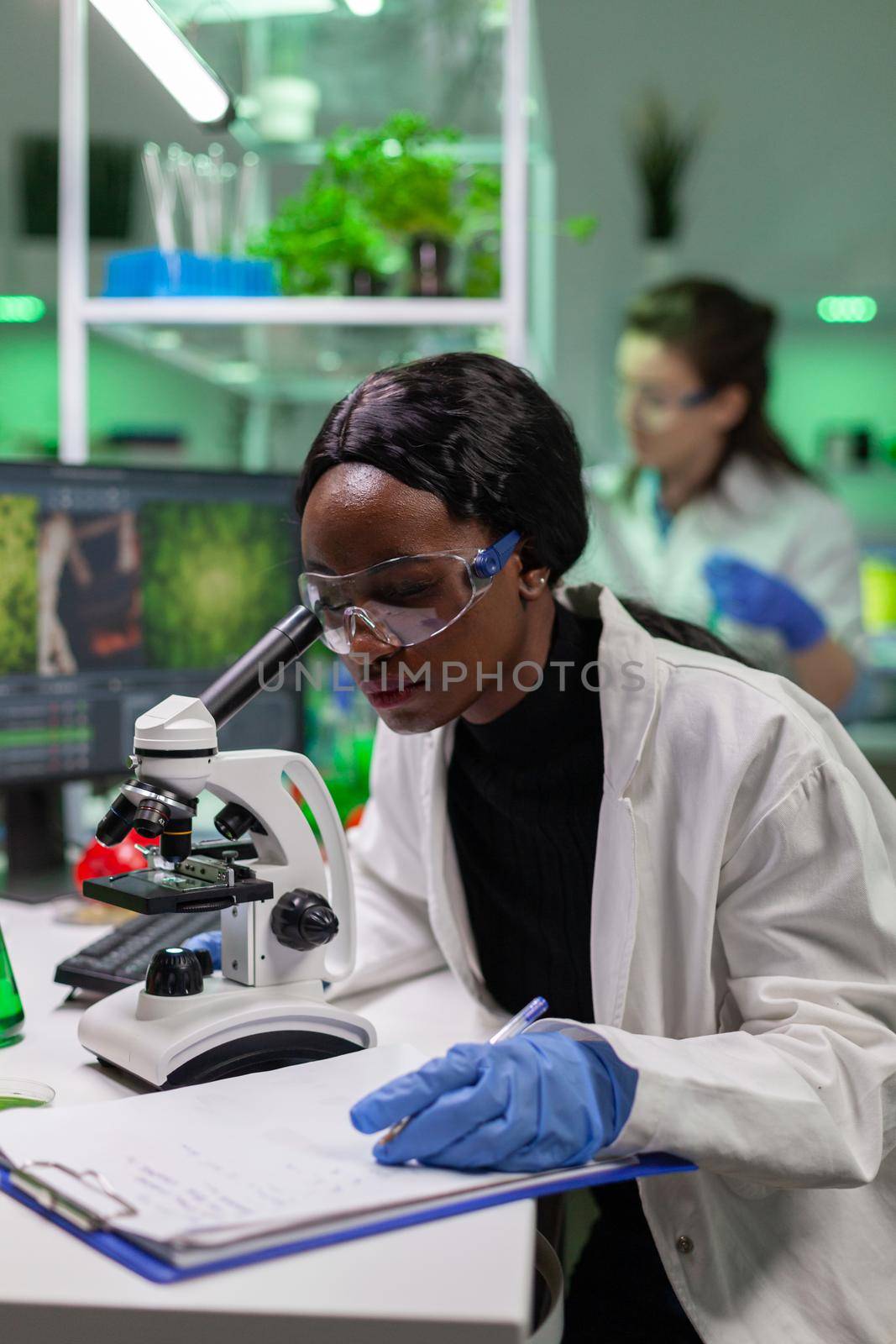 Biochemistry doctor examining chemical test using microscope for genetic researcher. Biologist specialist discovery organic gmo plants while working in microbiology food laboratory.