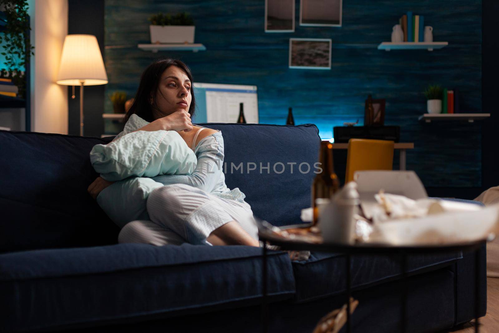 Depressed, frustrated, stressed, traumatised woman sitting alone holding pillow by DCStudio