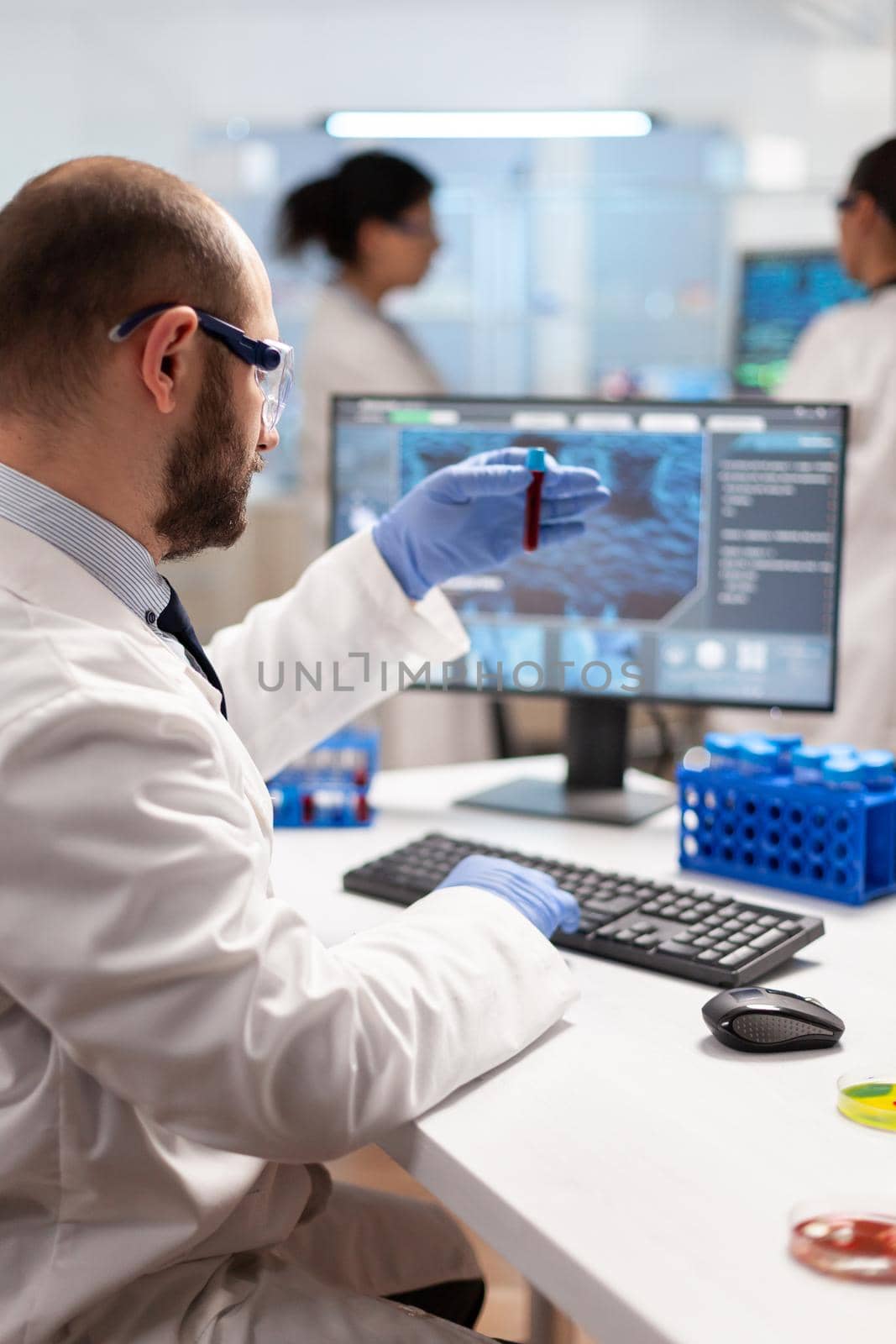 Genetic scientist studying epidemics holding sample of blood in test tube. Viorolog in professional lab analysing vaccine evolution, using modern technology, epidemics, health innovation.