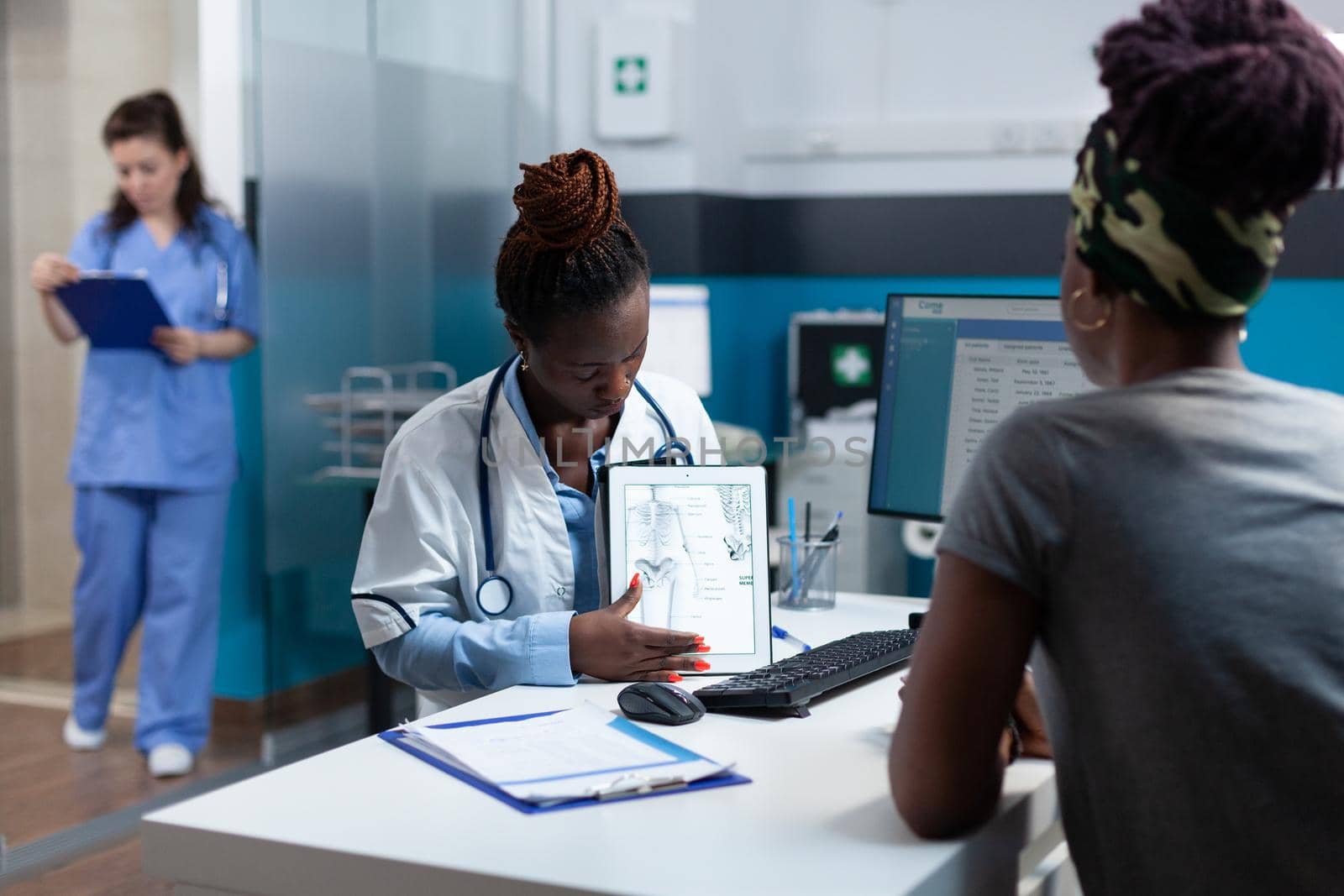 African american practitioner explaining radiology expertise discussing healthcare treatment with sick patient during clinical examination in hospital office. Radiologist doctor analyzing bones xray