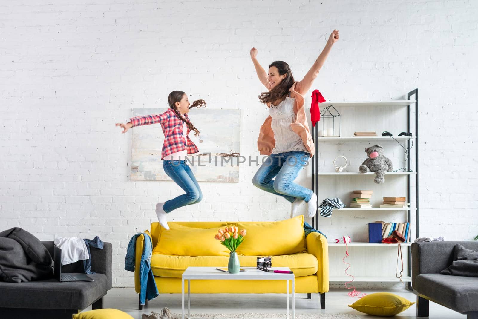 mother daughter jumping couch. High resolution photo