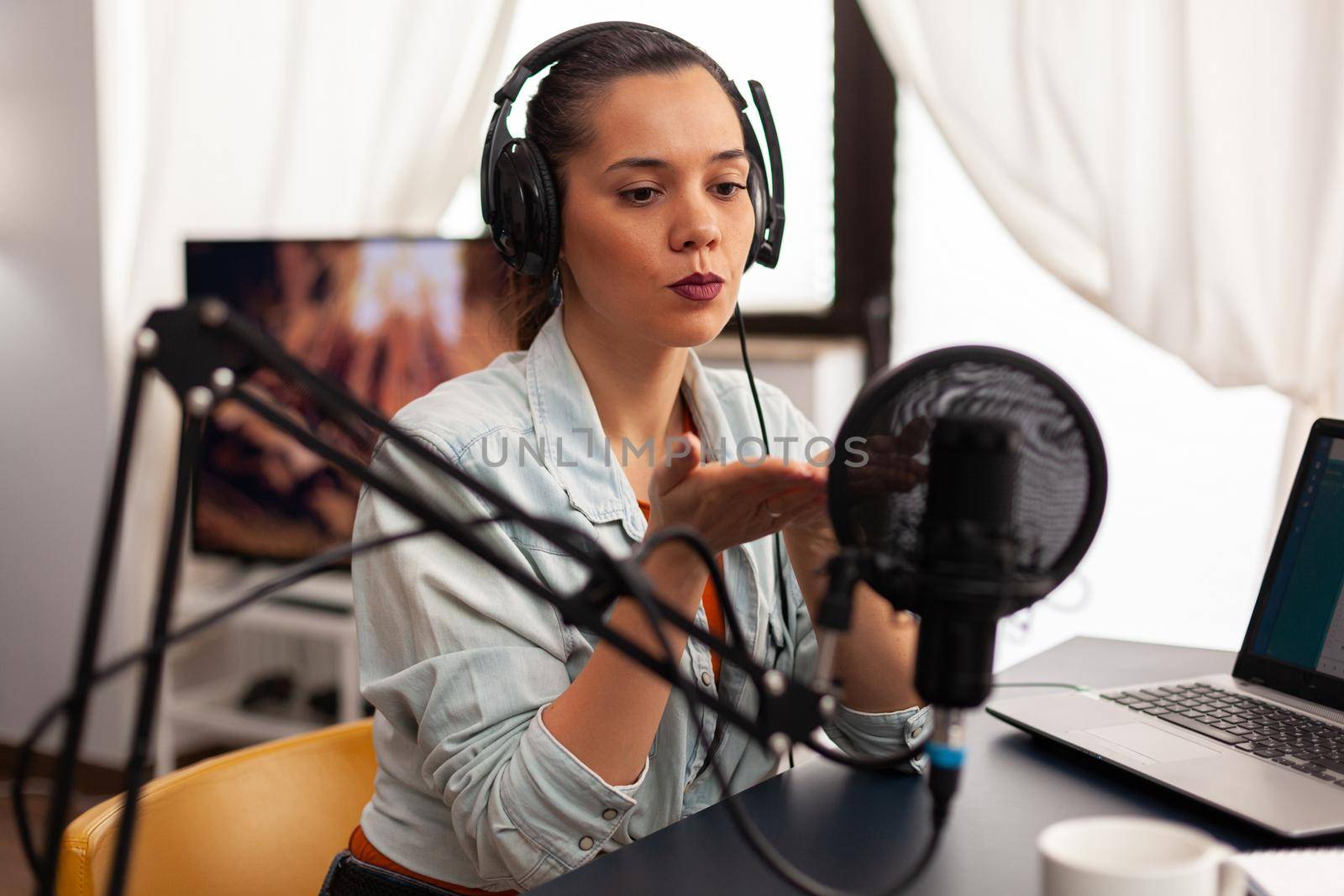 Influencer content creator blowing kisses in digital marketing concepts. Blogger speaking and recording online talk show at studio using headset, professional microphone looking at camera for podcast