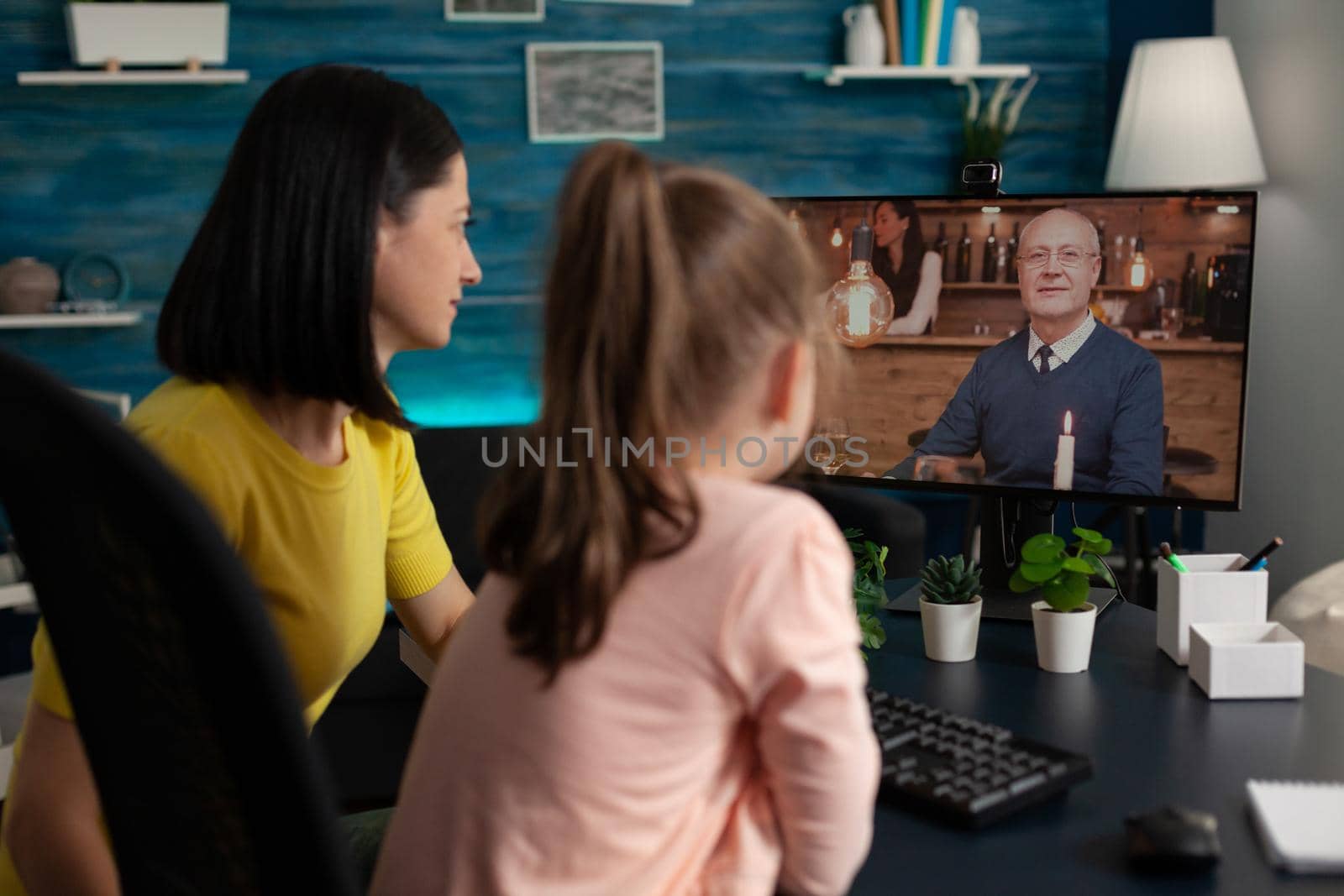 Smart school girl and mom on online conference video call using internet connection computer monitor screen to talk to distant grandfather. Caucasian family meeting on virtual website app