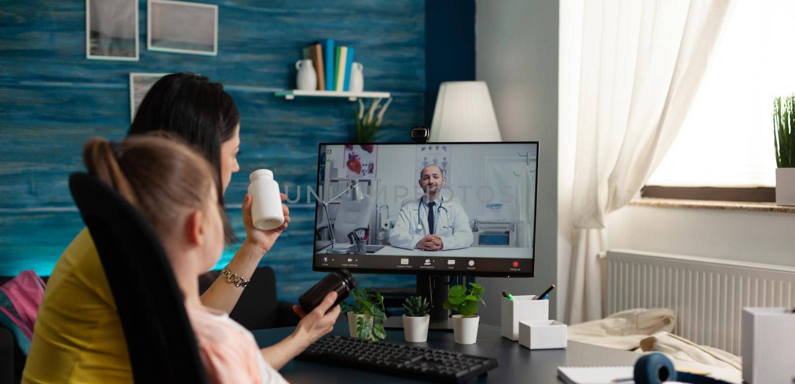 Family doctor giving prescription medicine consultation on video call with sick child patient and parent at home. Caucasian people using online conference meeting app for healing treatment