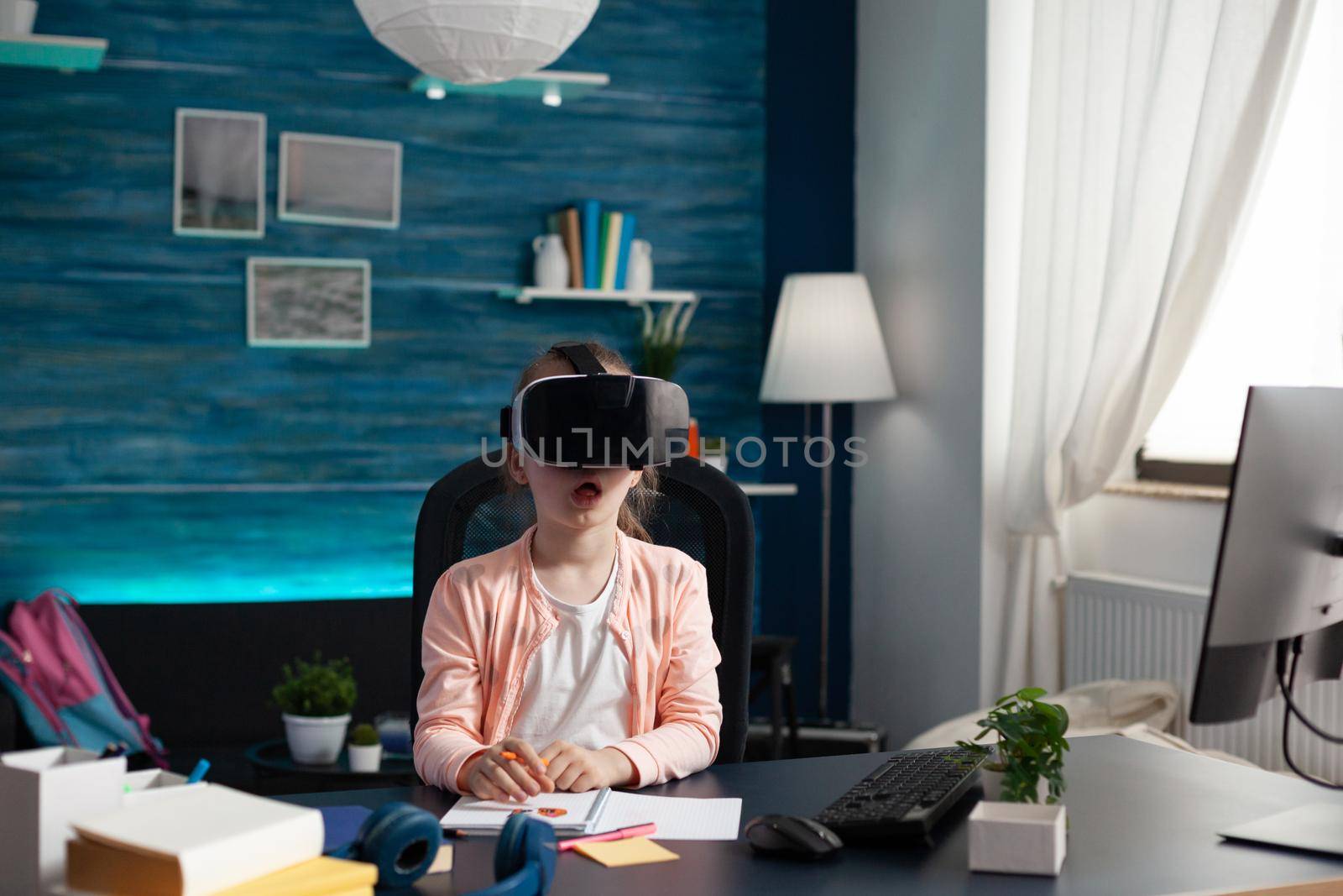 Little pupil at home desk using vr glasses for class by DCStudio